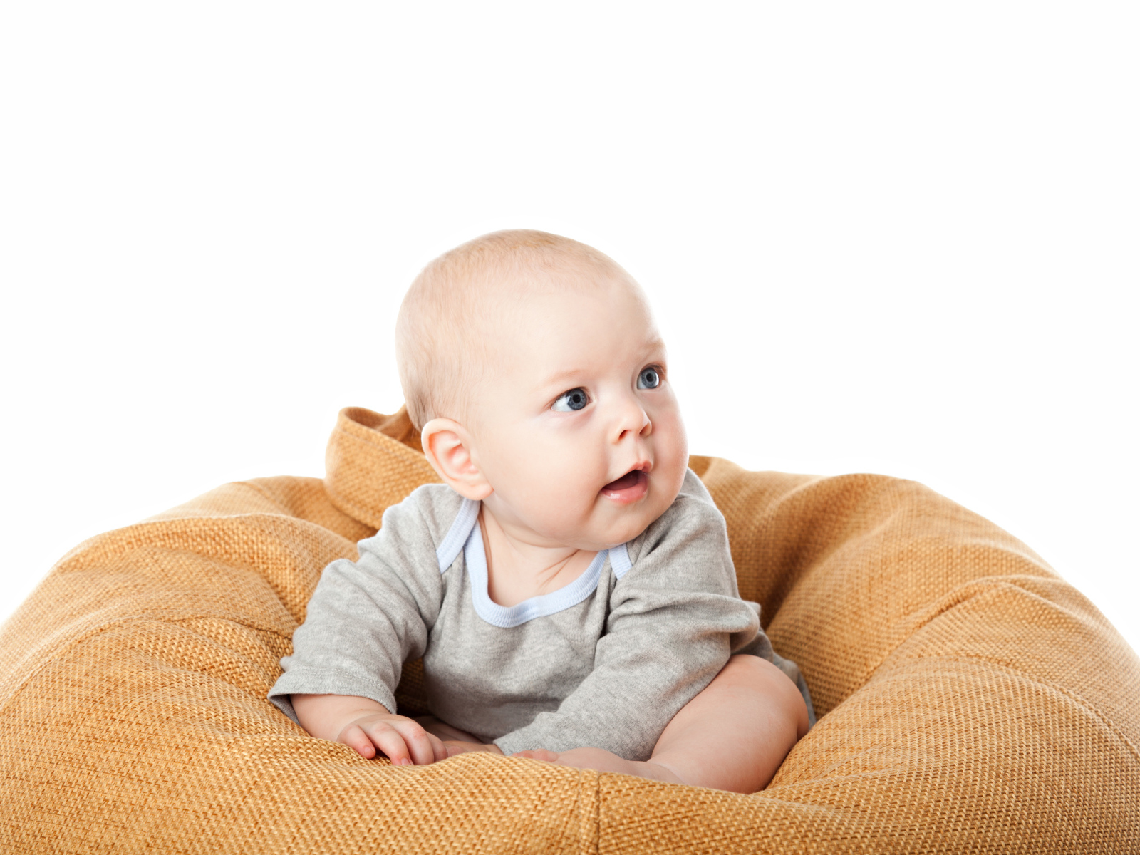 Младенец сидит на подушке на белом фоне