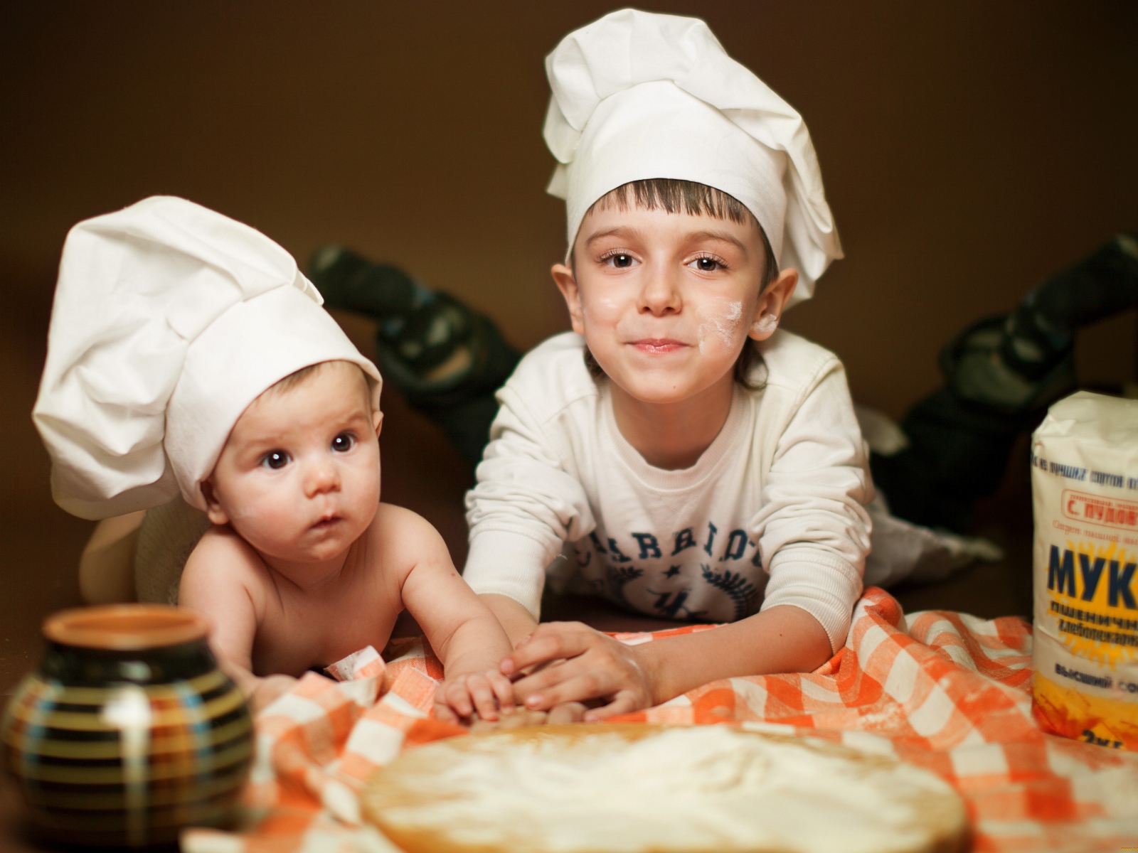 Два маленьких мальчика в шапках повара на кухне