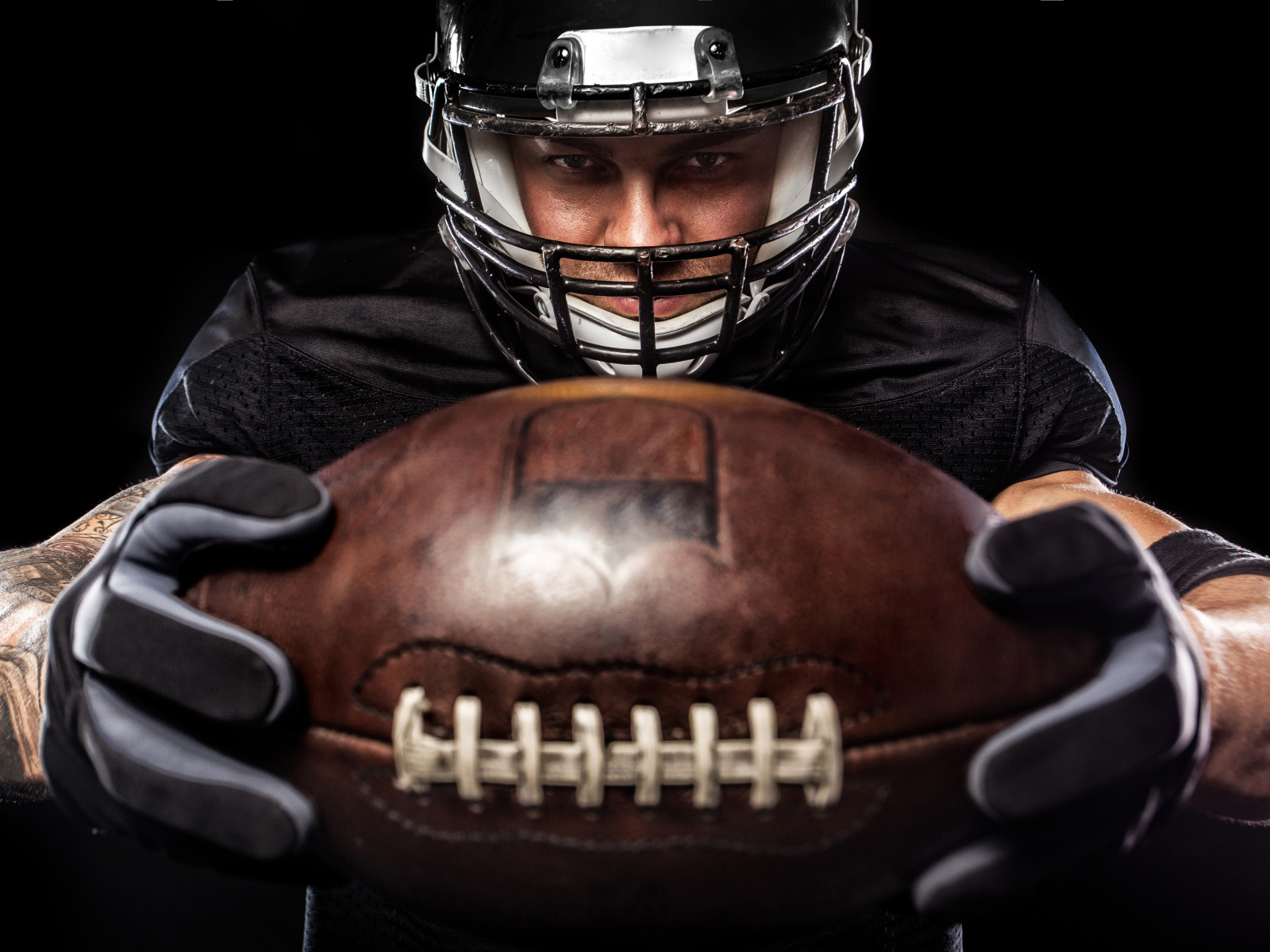 Американский футболист с мячом на черном фоне
