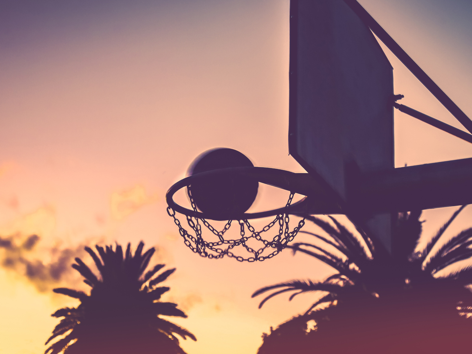 Баскетбольное кольцо с мячом на закате