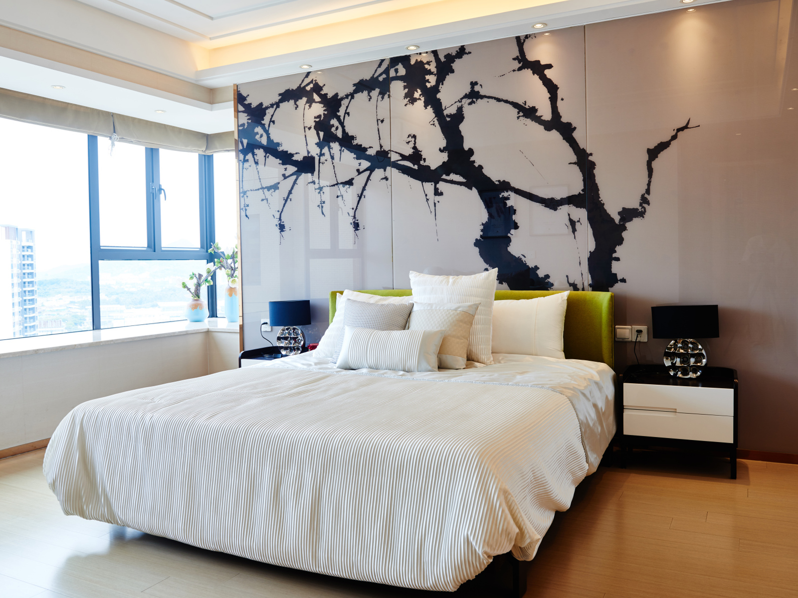 Красивая светлая спальня с большой кроватью и рисунком на стене 