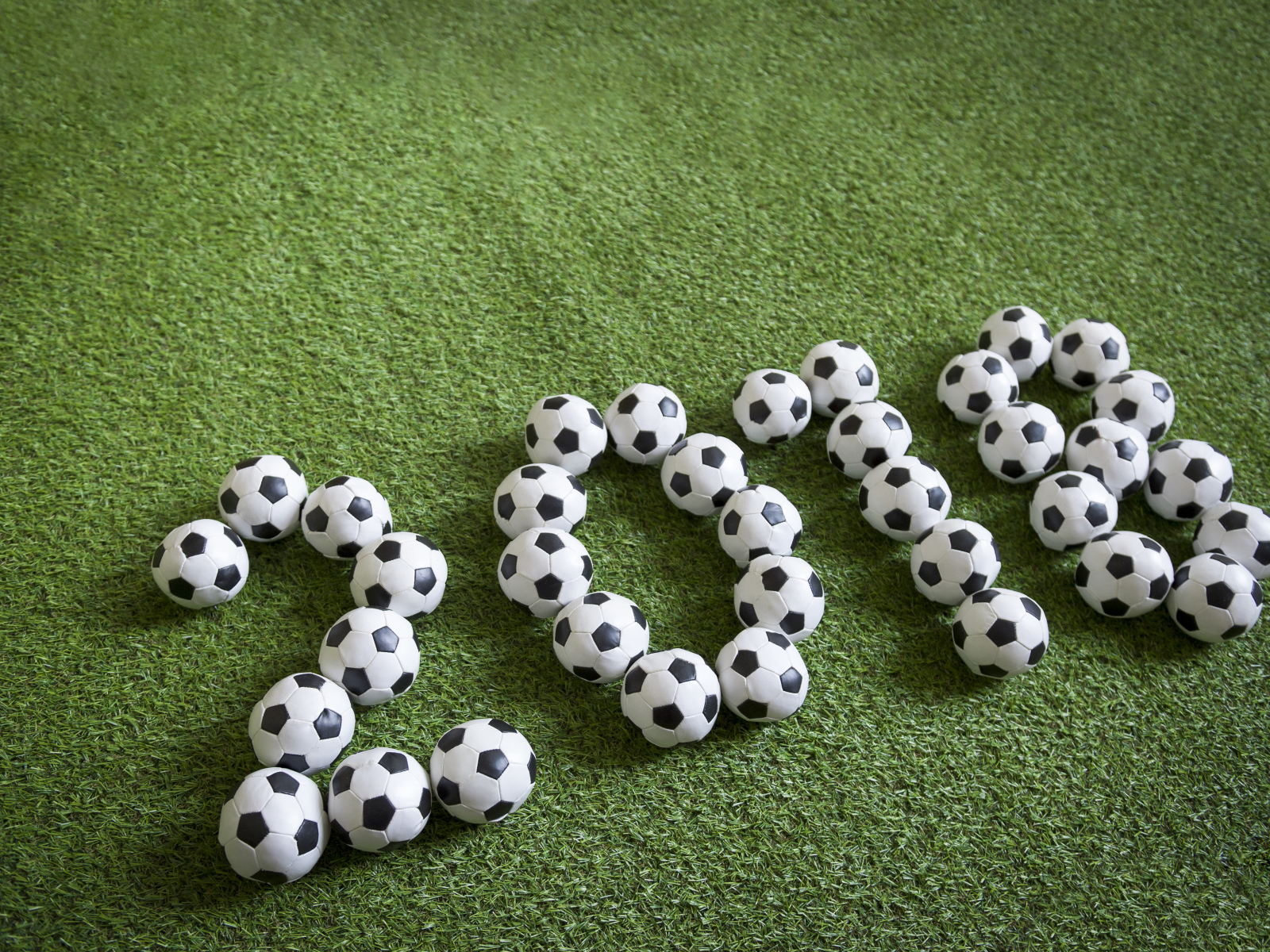 Цифры 2018 из футбольных мячей на зеленой траве