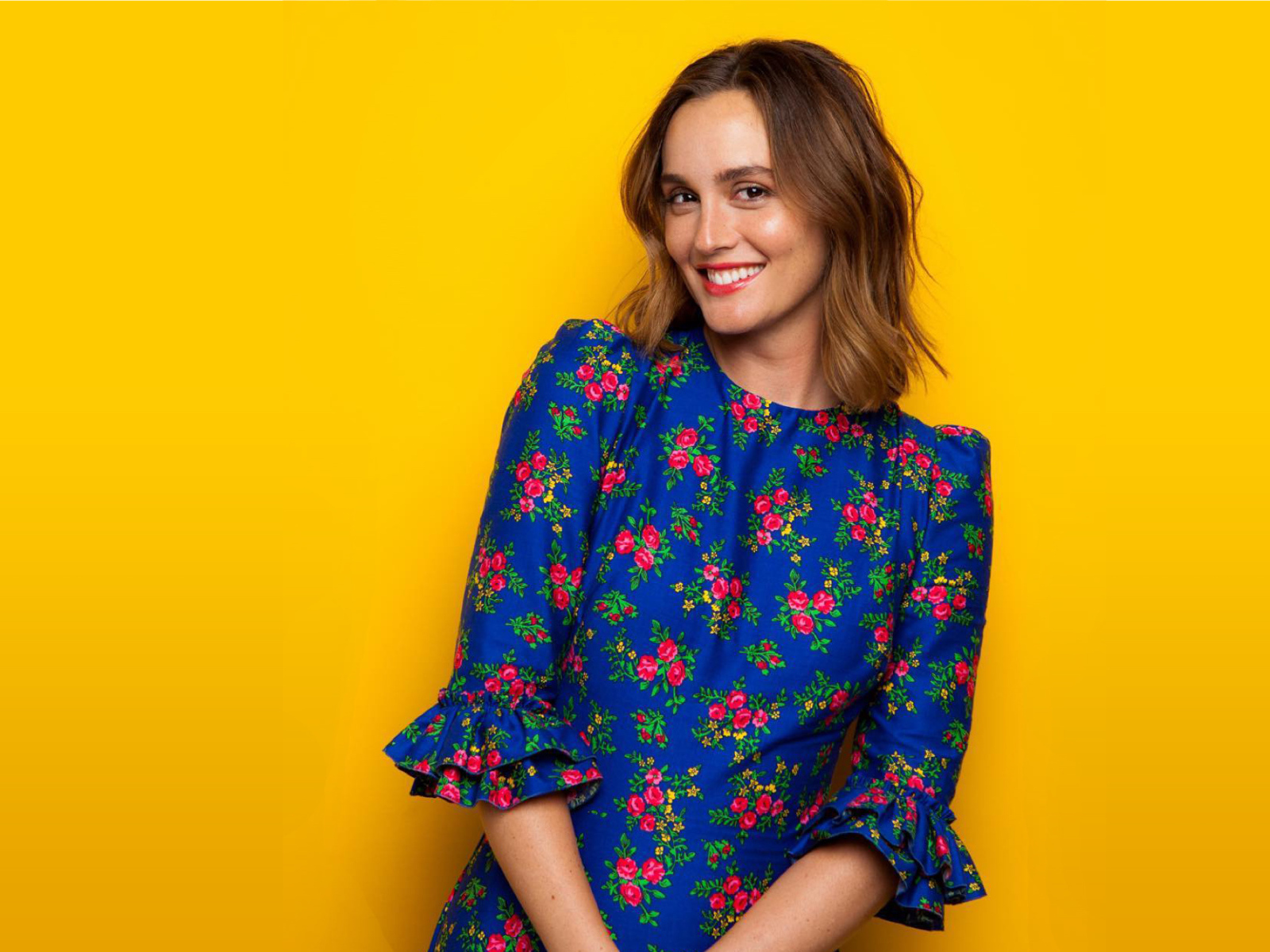 Улыбающаяся актриса Лейтон Мистер в красивом платье на желтом фоне 