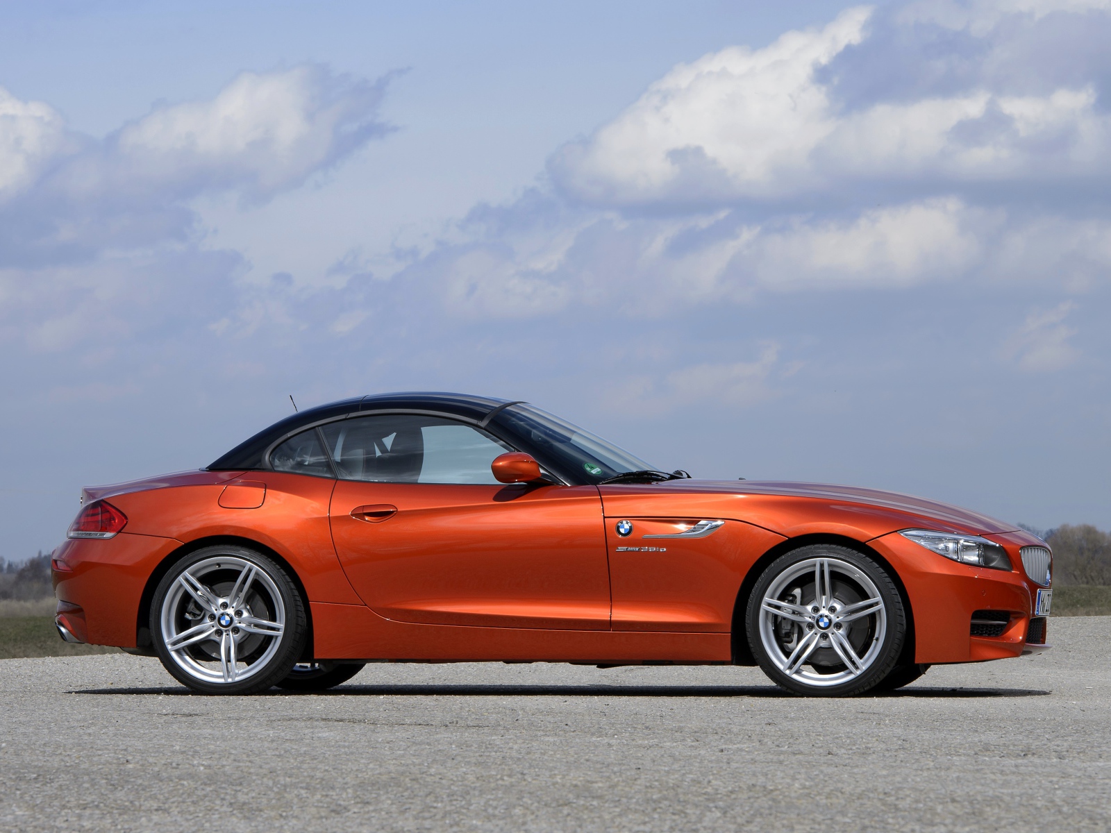 Оранжевый автомобиль BMW Z4 на фоне красивого неба