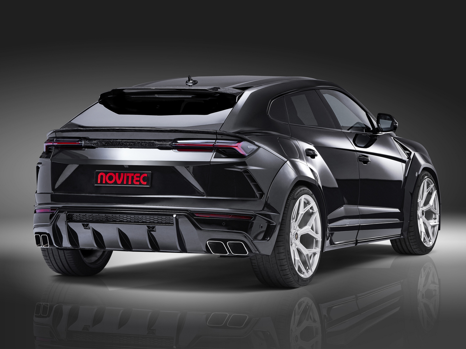 Черный Novitec Lamborghini Urus Esteso 2019 года вид сзади на сером фоне