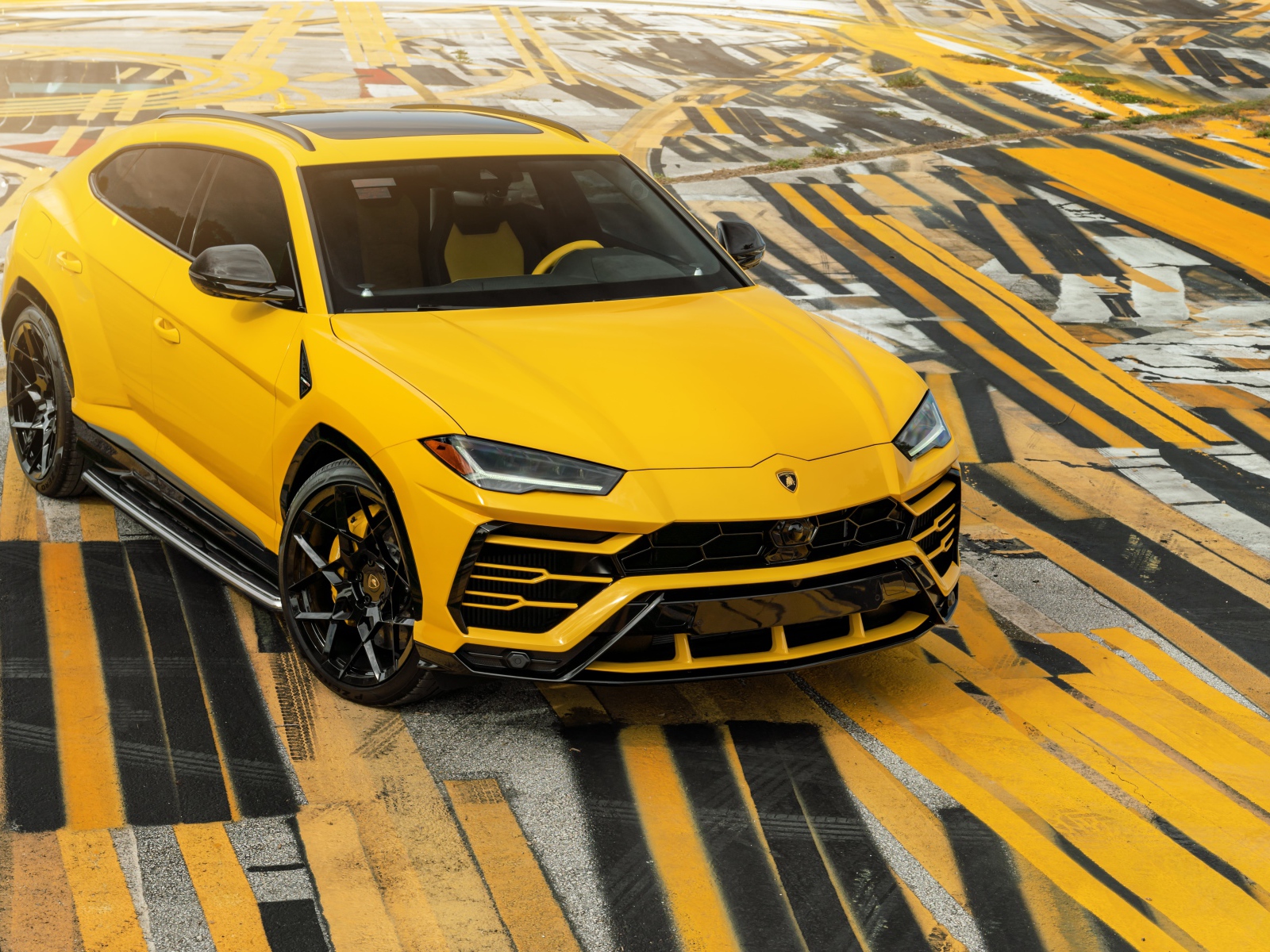 Желтый внедорожник Lamborghini Urus на разноцветном асфальте 