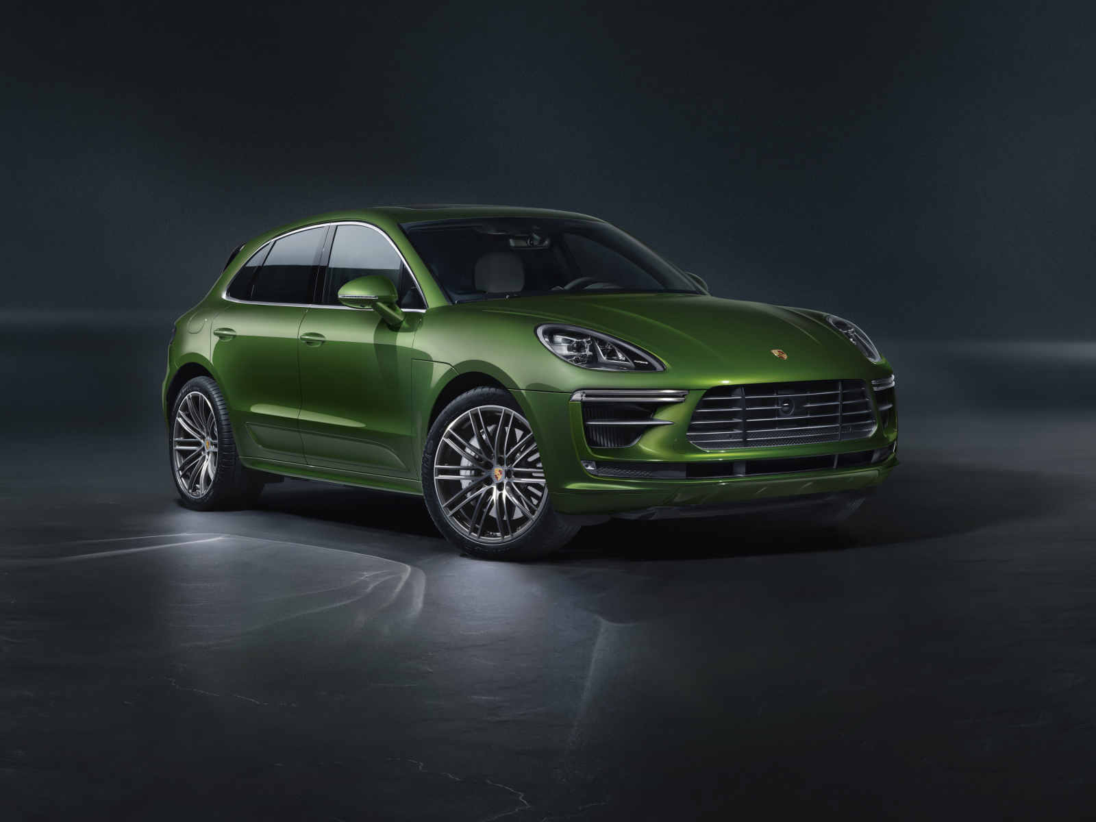 Зеленый автомобиль Porsche Macan Turbo 2019 года на сером фоне