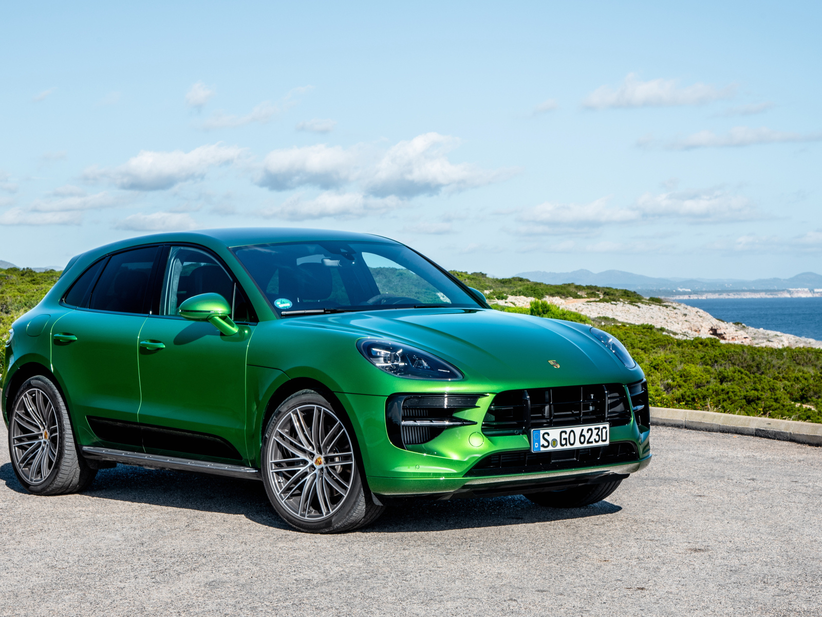 Зеленый внедорожник Porsche Macan S,  2018 года на фоне горизонта 