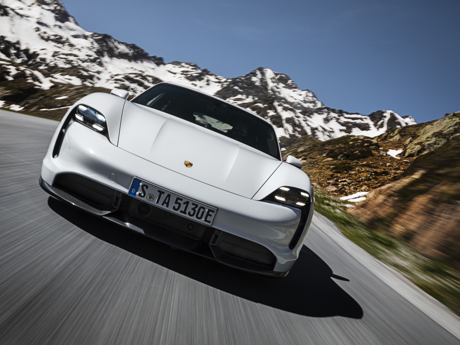 Белый автомобиль Porsche Taycan Turbo S 2019 года на фоне заснеженных гор