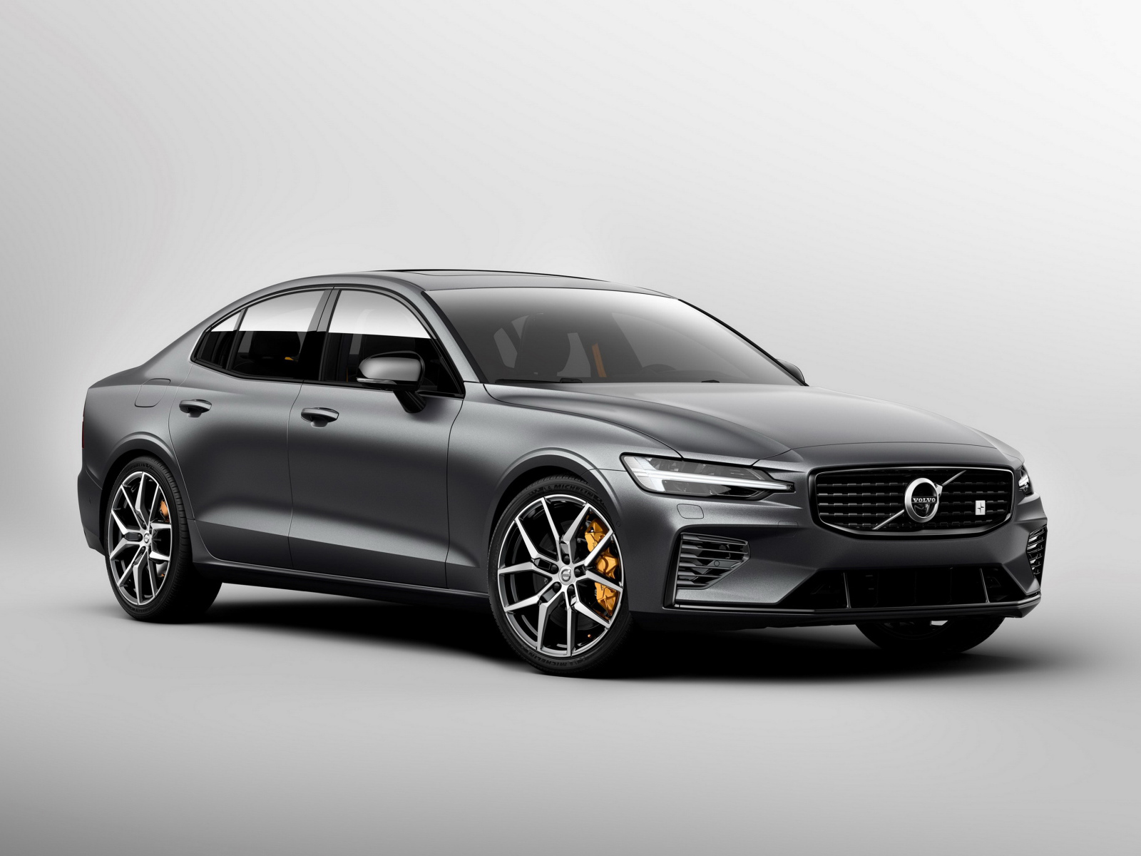 Серебристый автомобиль Volvo S60, 2018 года на сером фоне