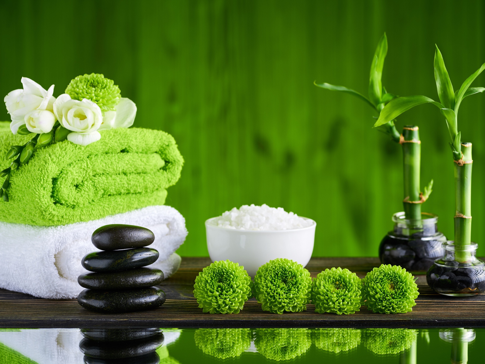 Черные камни, полотенца, соль и цветы у воды для SPA