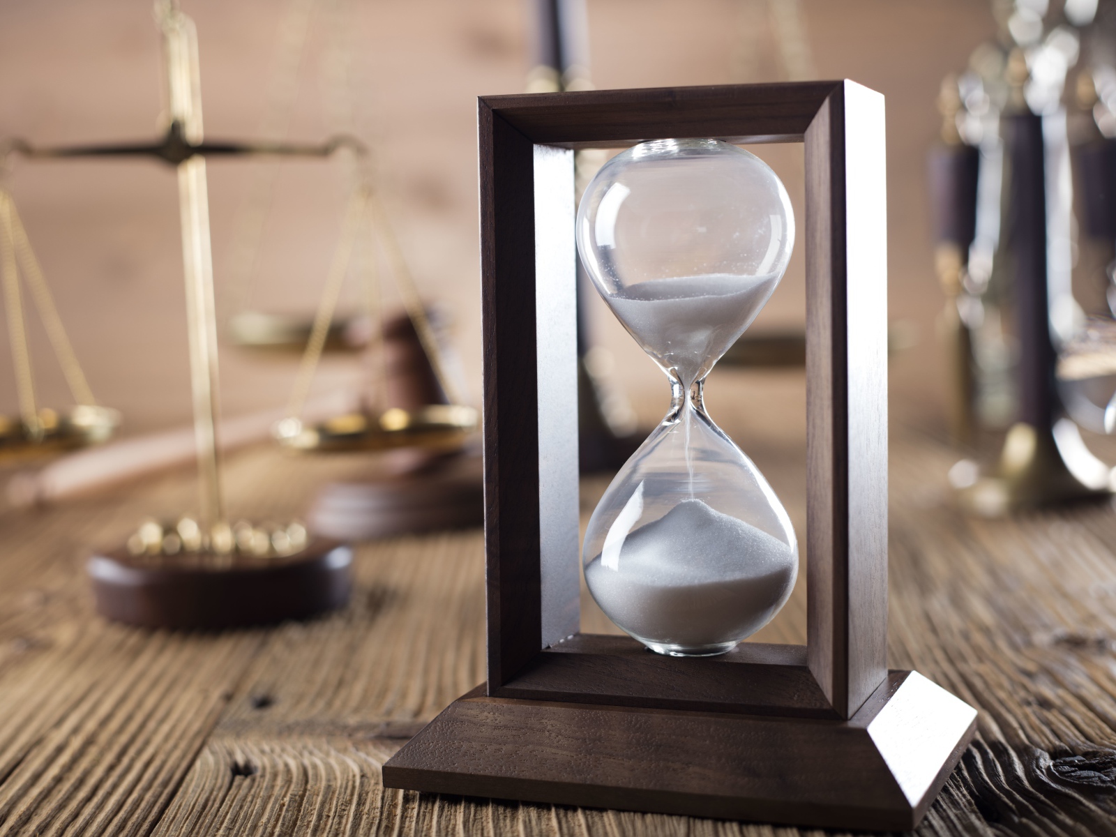 Песочные часы на столе с весами крупным планом