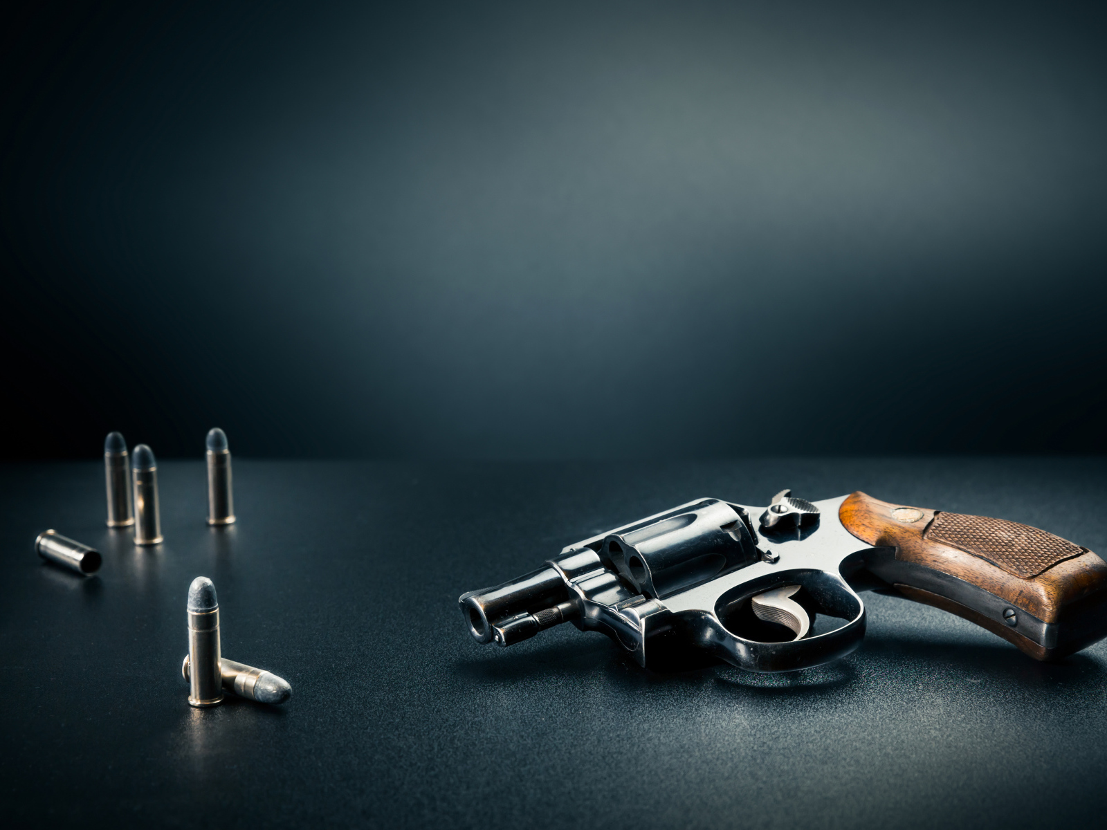 Револьвер с пулями на сером фоне