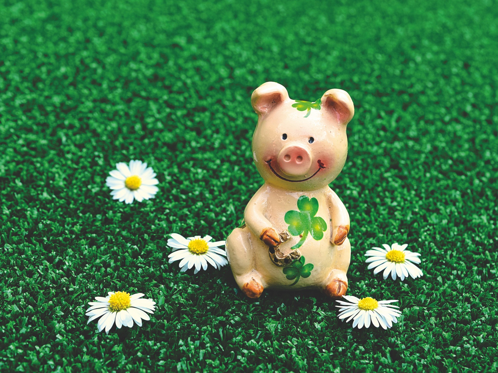 Статуэтка поросенка на зеленой траве с ромашками