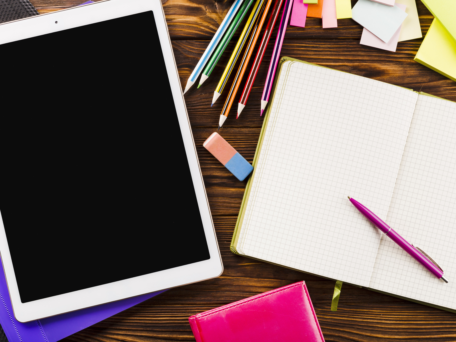 Планшет на столе с блокнотом и карандашами