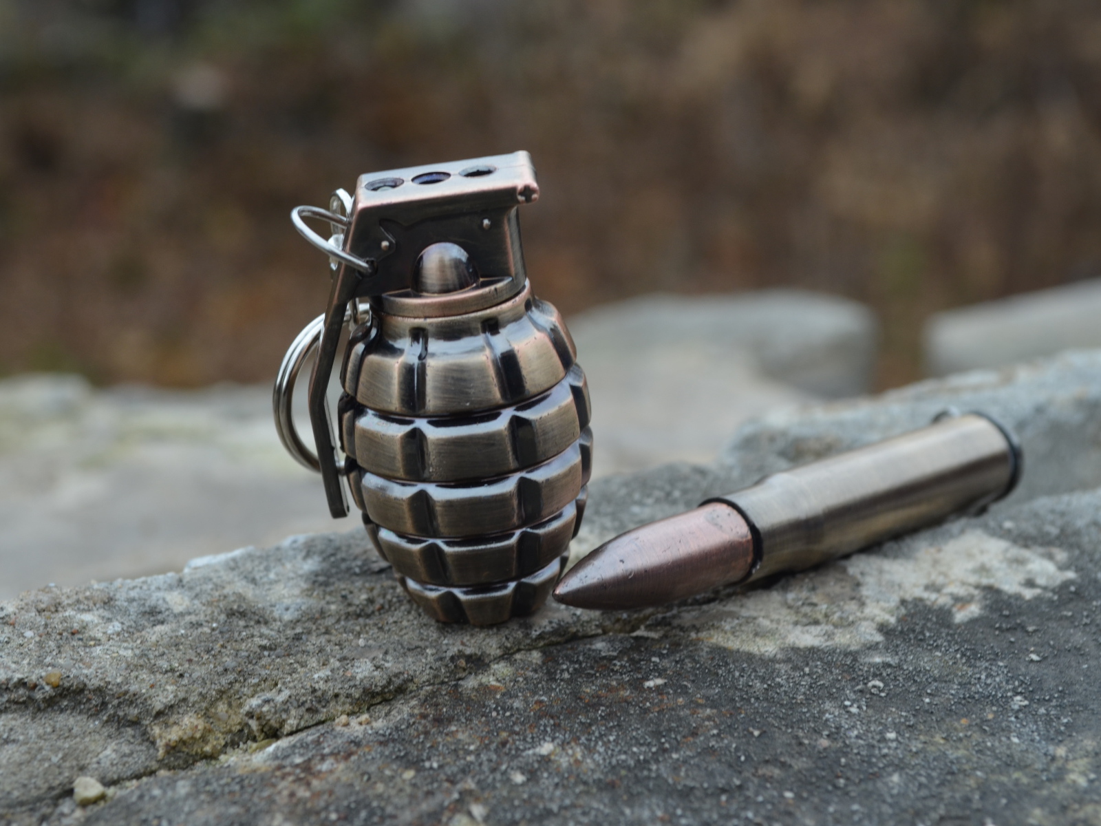 Боевая граната с патроном лежат на камне 