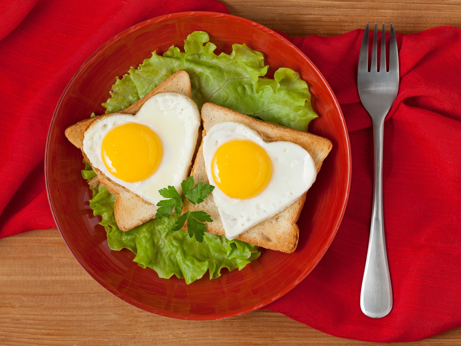 Гренки с яичницей на тарелке с листьями салата 