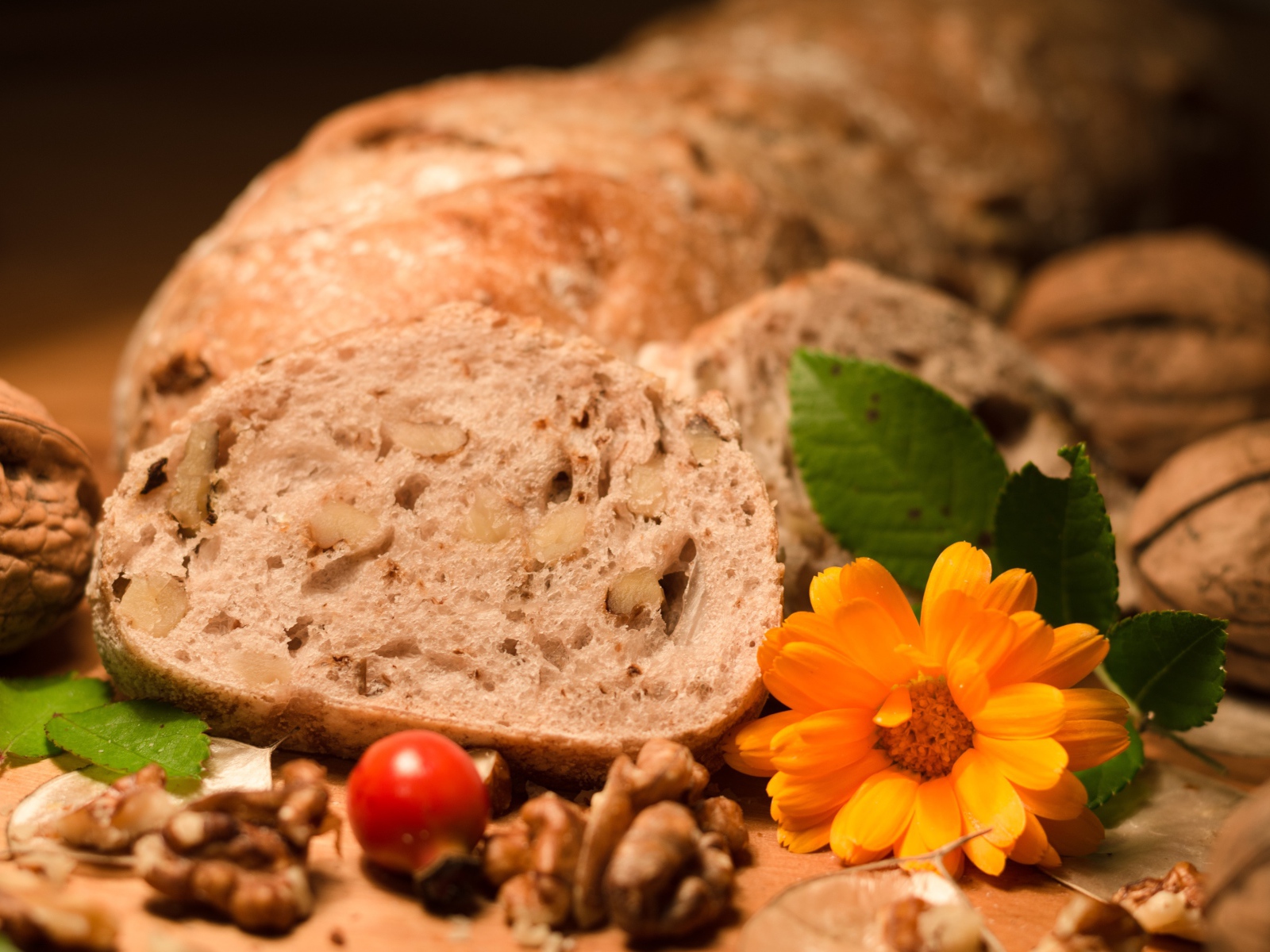Свежий хлеб с грецкими орехами и цветами календулы на столе
