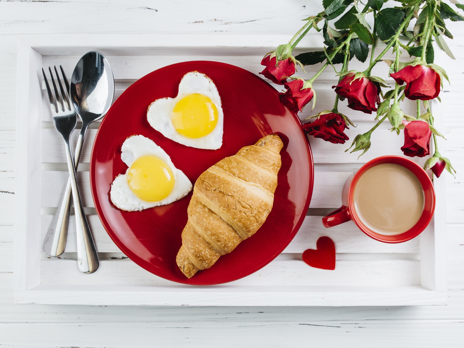 Яичница с круассаном на красной тарелке на столе букетом роз и чашкой какао