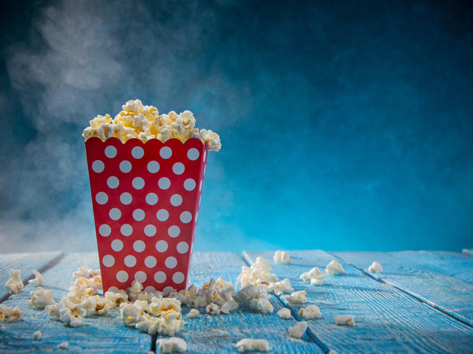 Попкорн в картонном пакете на голубом столе 