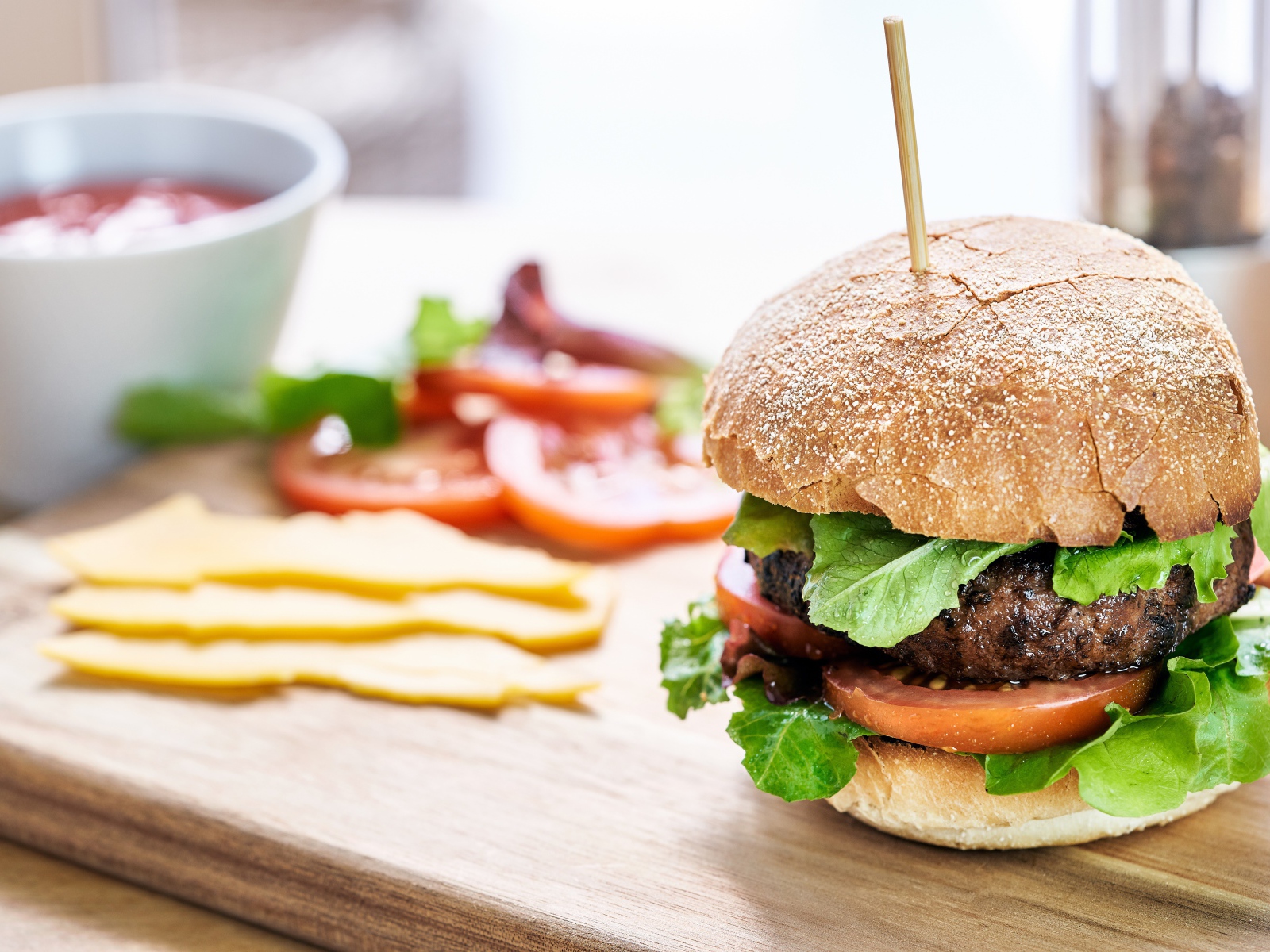 Аппетитный гамбургер на доске с сыром и помидорами