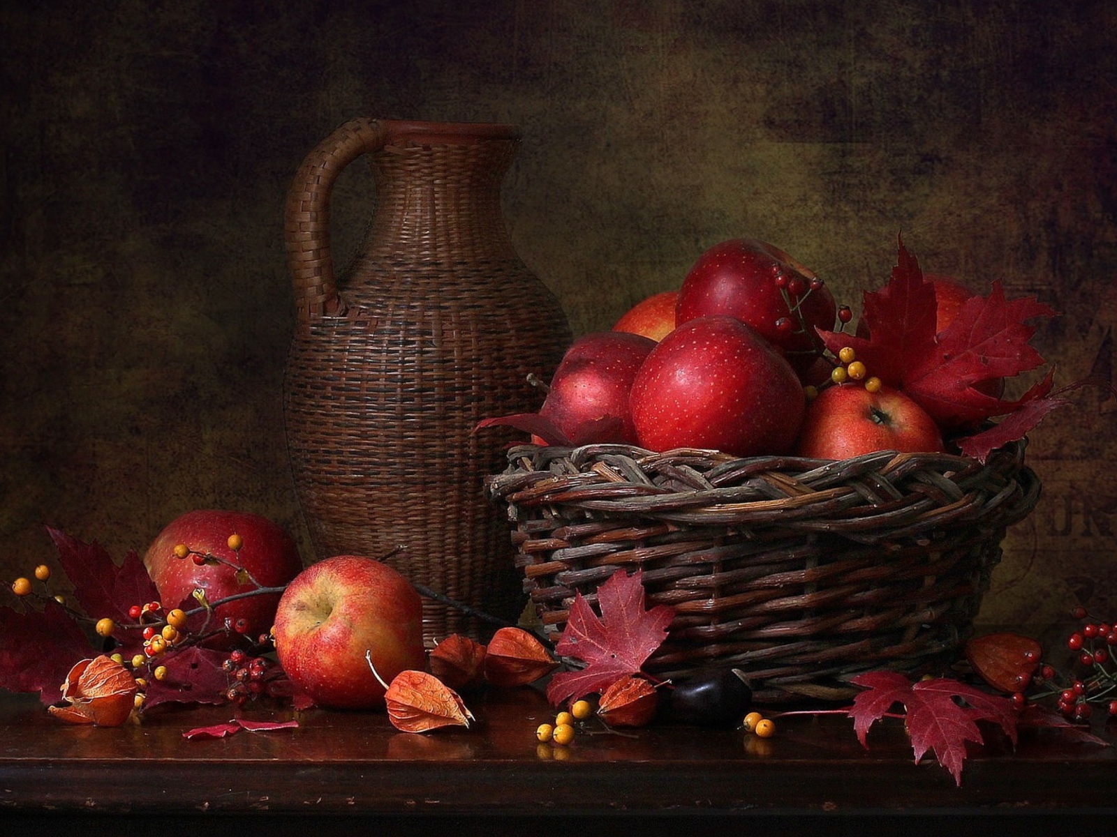Корзина с красными яблоками на столе с кувшином 