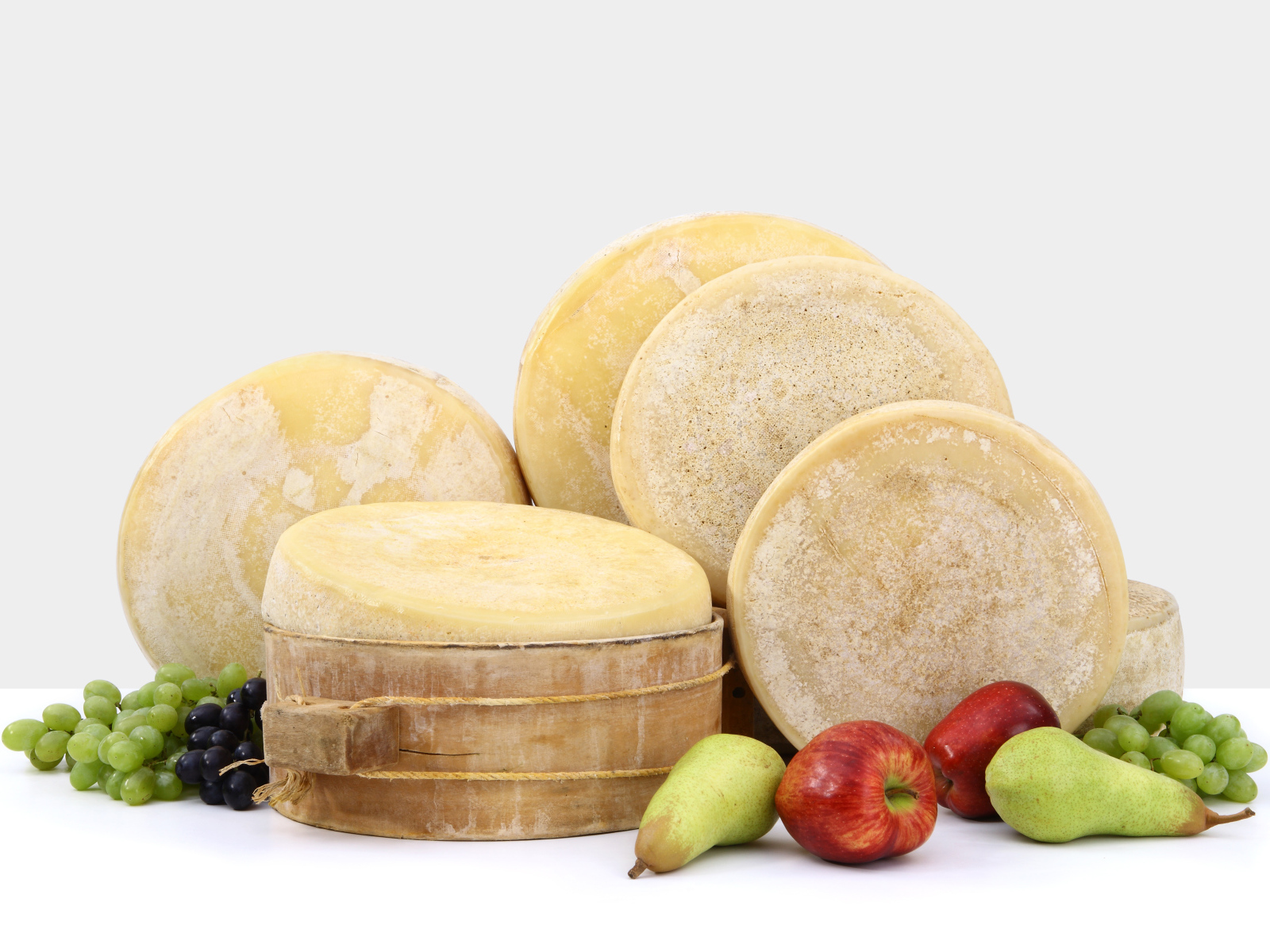 Сыр на столе с грушами, яблоками и виноградом
