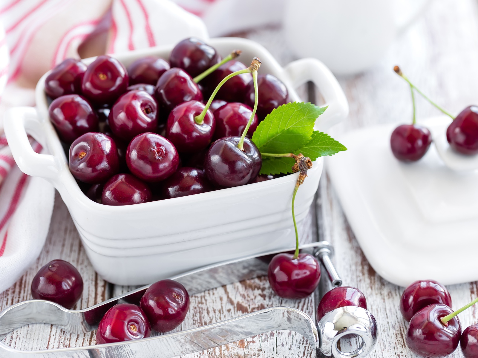Красные спелые вишни в белой тарелке на столе