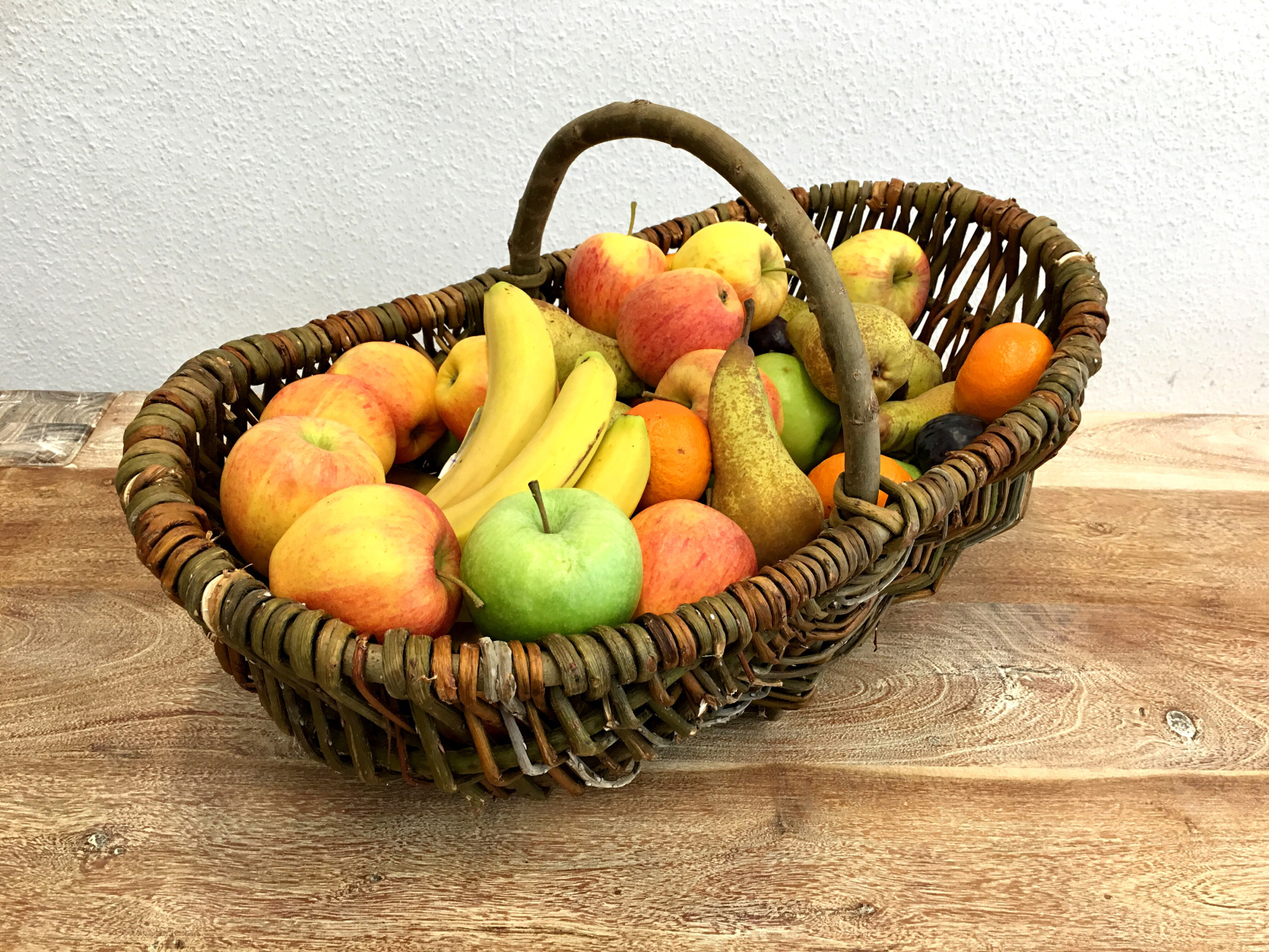 Спелые фрукты в плетеной корзине на столе