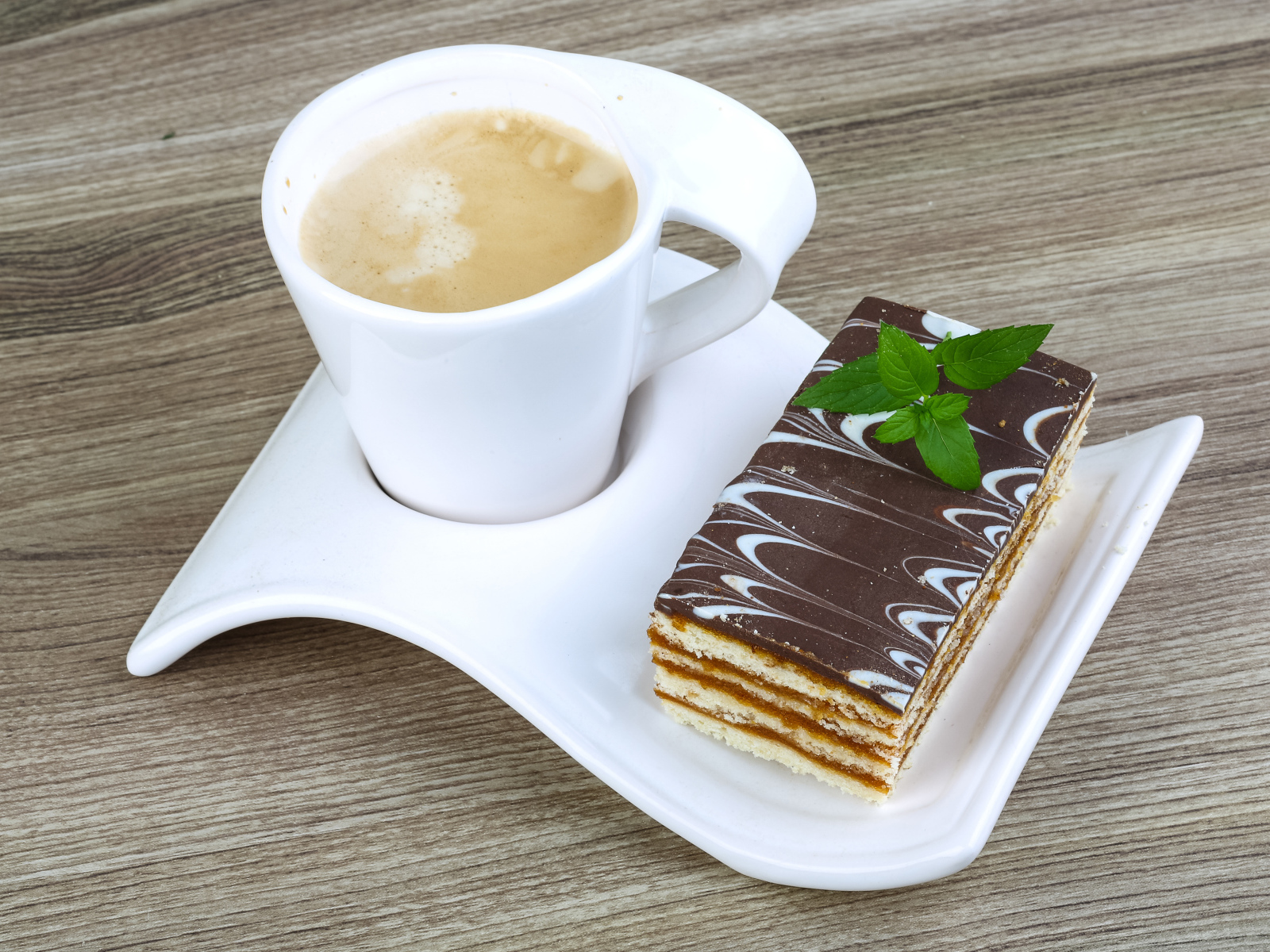 Чашка капучино на тарелке с пирожным 