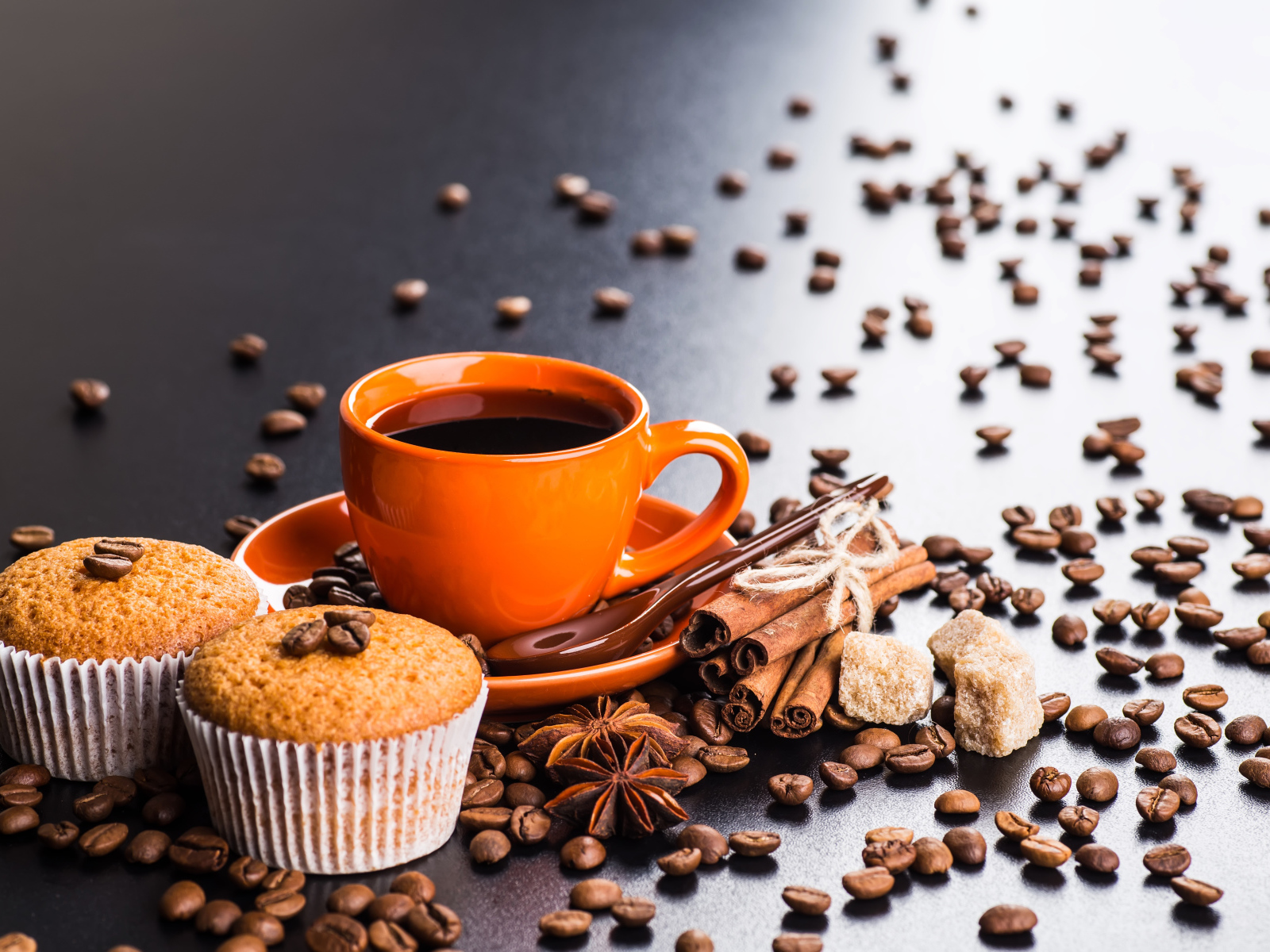 Чашка кофе на столе с кексами, кофейными зернами, корицей и бадьяном