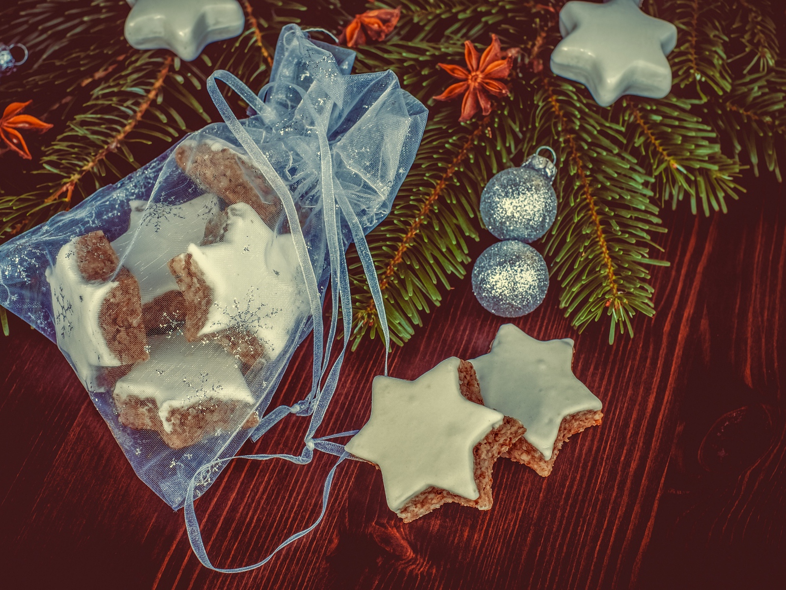 Аппетитное печенье звездочки в мешочке на столе с еловой веткой
