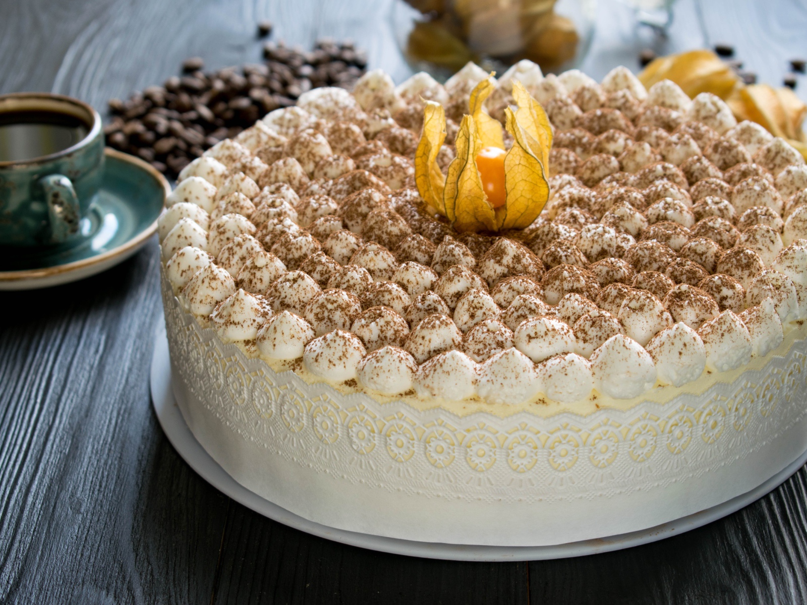 Красивый праздничный торт с цветком физалиса на столе с кофе