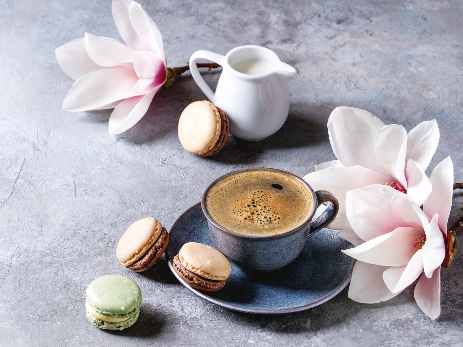 Кофе на столе с макарунами, молоком и цветами 