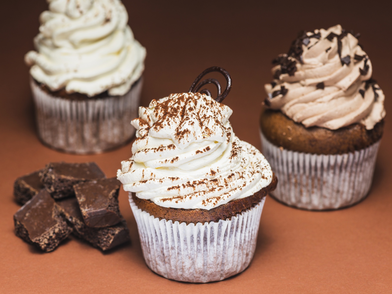 Кексы с кремом на столе с кусочками шоколада 