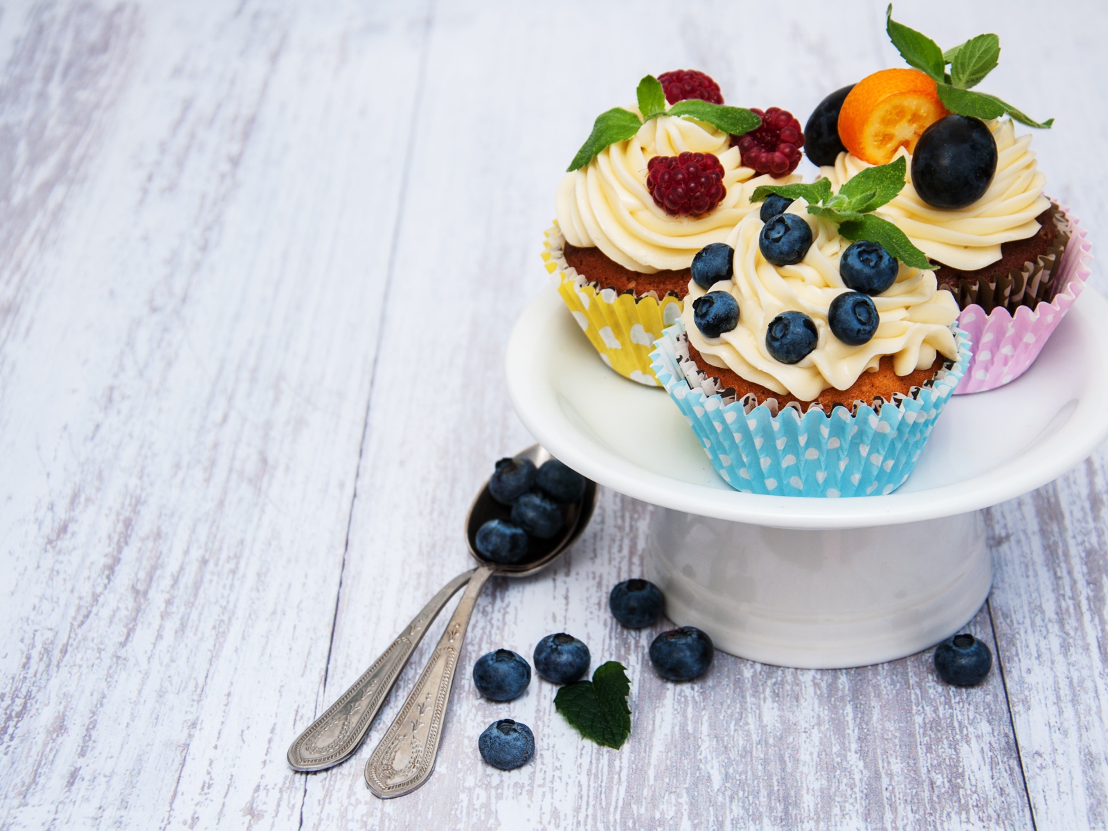 Cupcakes with cream on a white dish with berries