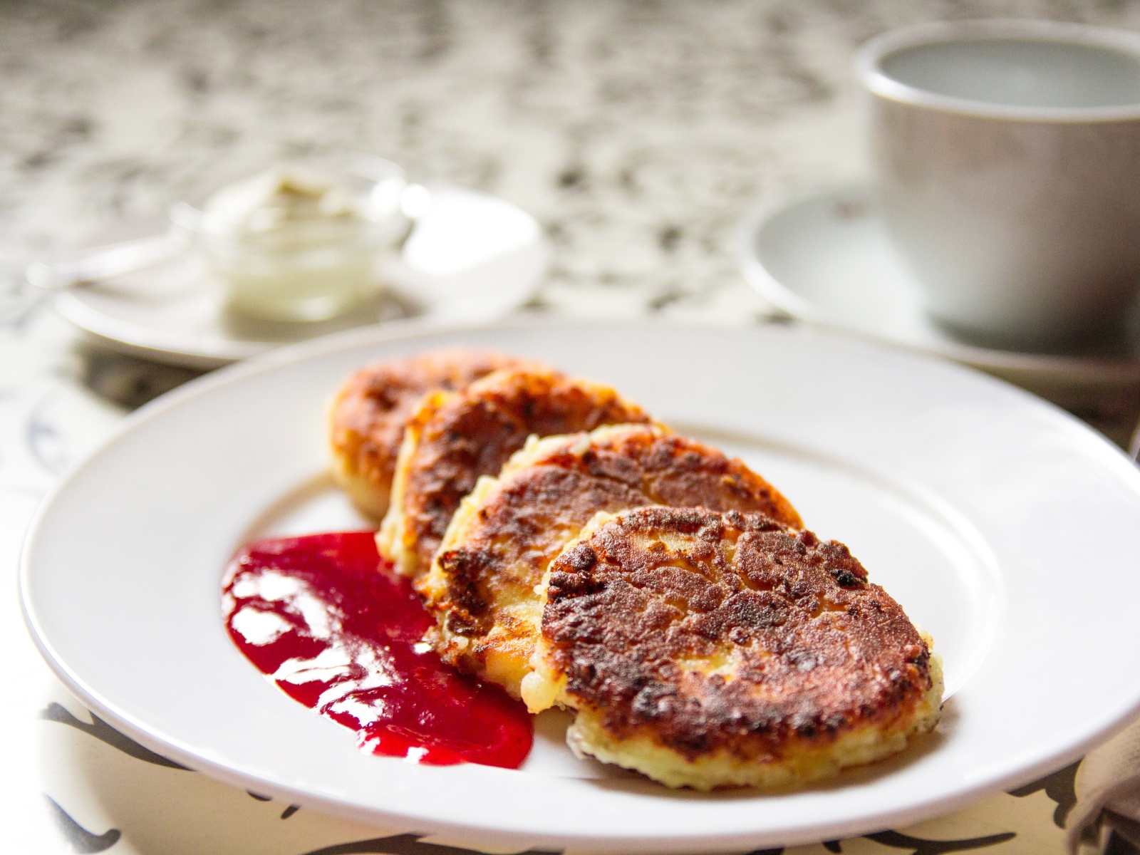 Аппетитные сладкие сырники с джемом на белой тарелке