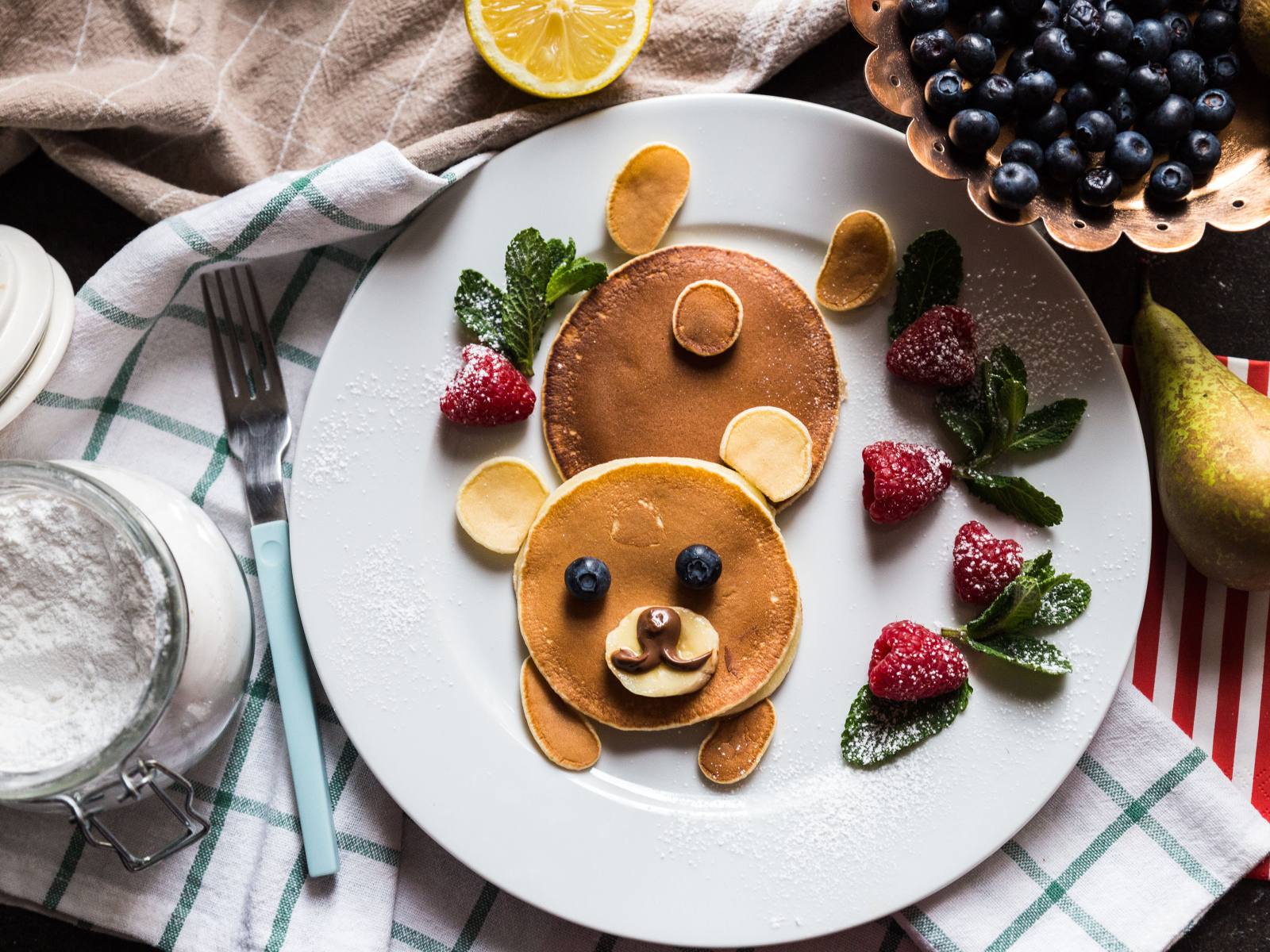 Медведь из оладьев на тарелке с малиной и сахарной пудрой