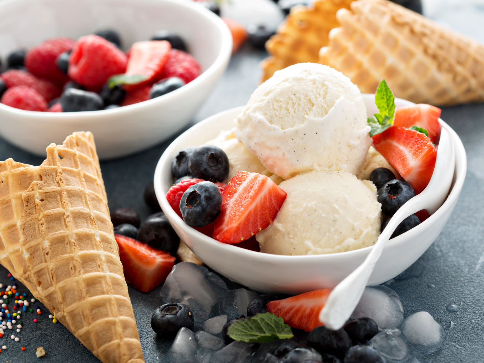 Мороженое с ягодами черники и клубники на столе с вафельными рожками