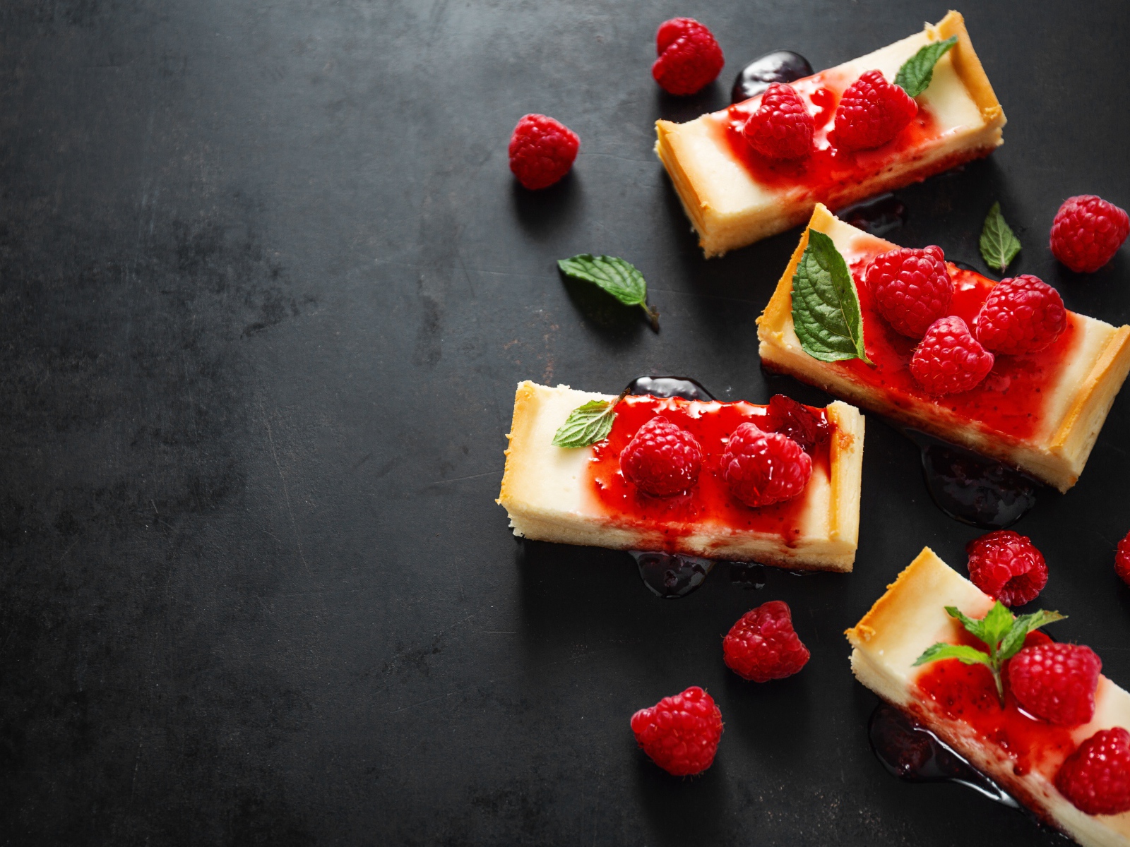 Куски чизкейка на столе с джемом и ягодами малины