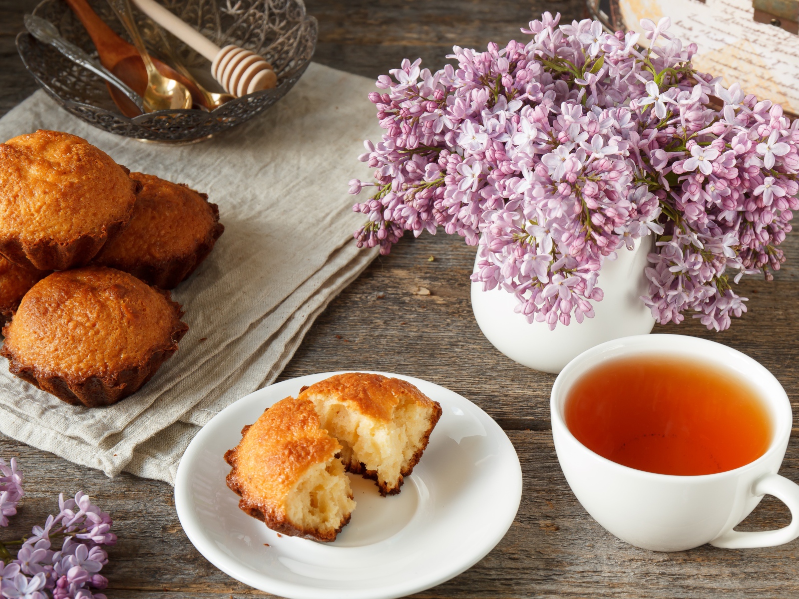 Сладкие кексы на столе с чаем и букетом сирени