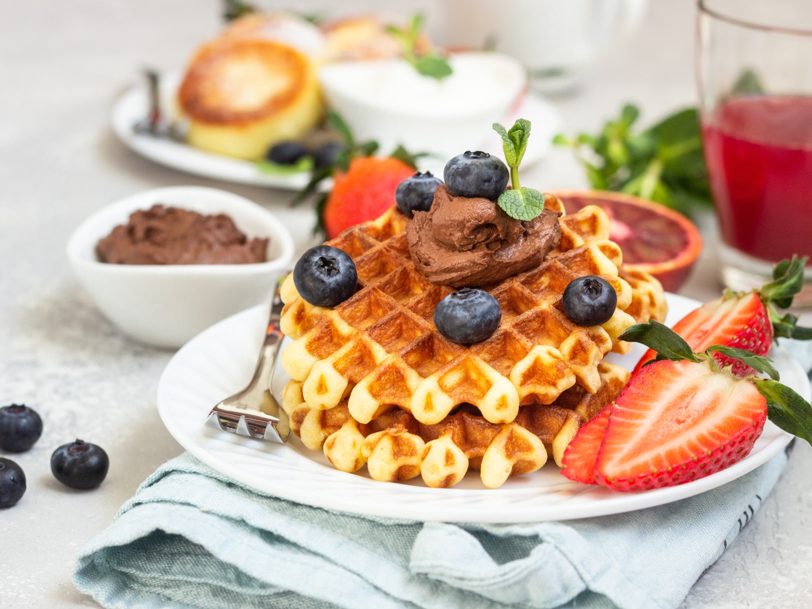 Сладкая вафля с шоколадом, ягодами черники и клубники на тарелке