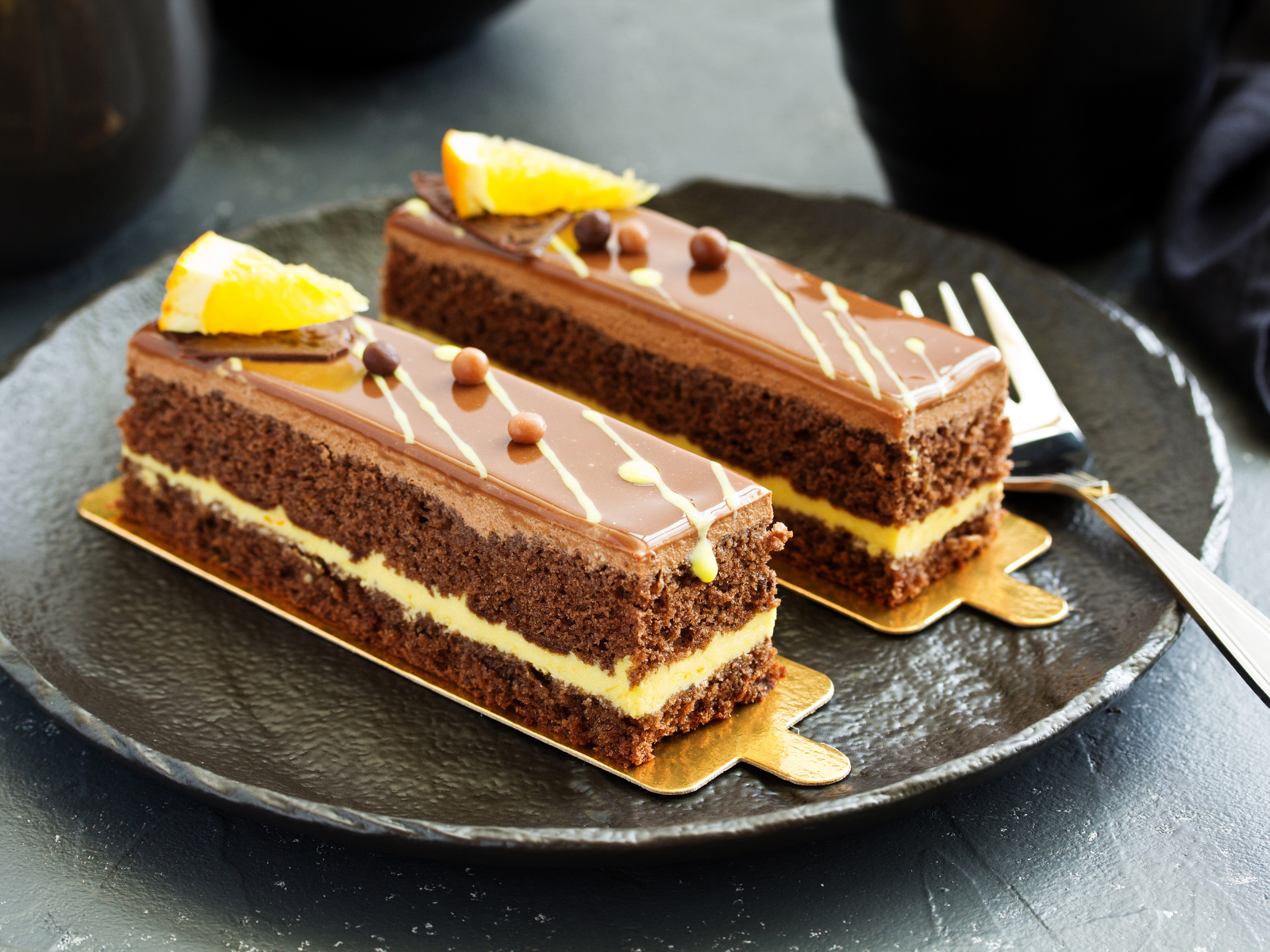 Два вкусных шоколадных пирожный на большой тарелке с вилкой