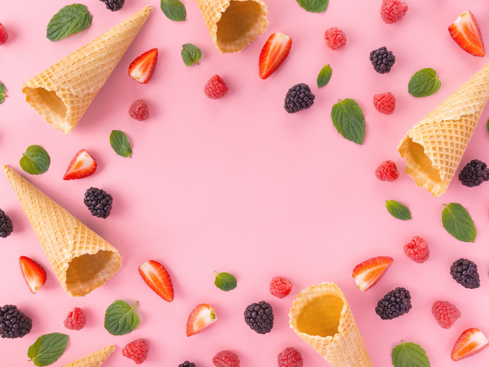 Waffle cones on a pink background with berries of raspberry, strawberry and blackberry