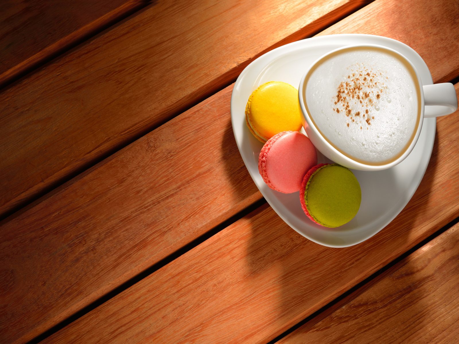 Чашка капучино на блюдце с печеньем макарон