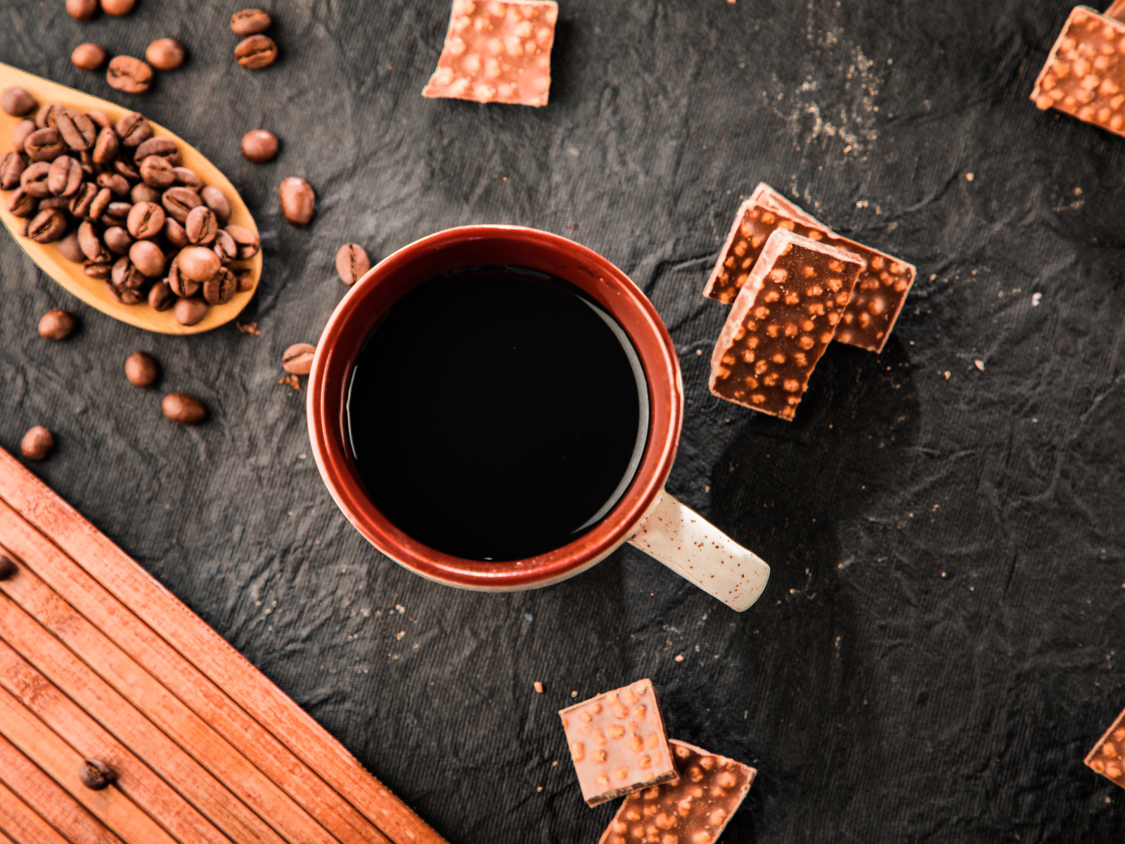 Чашка кофе на столе с кусочками шоколада и кофейными зернами
