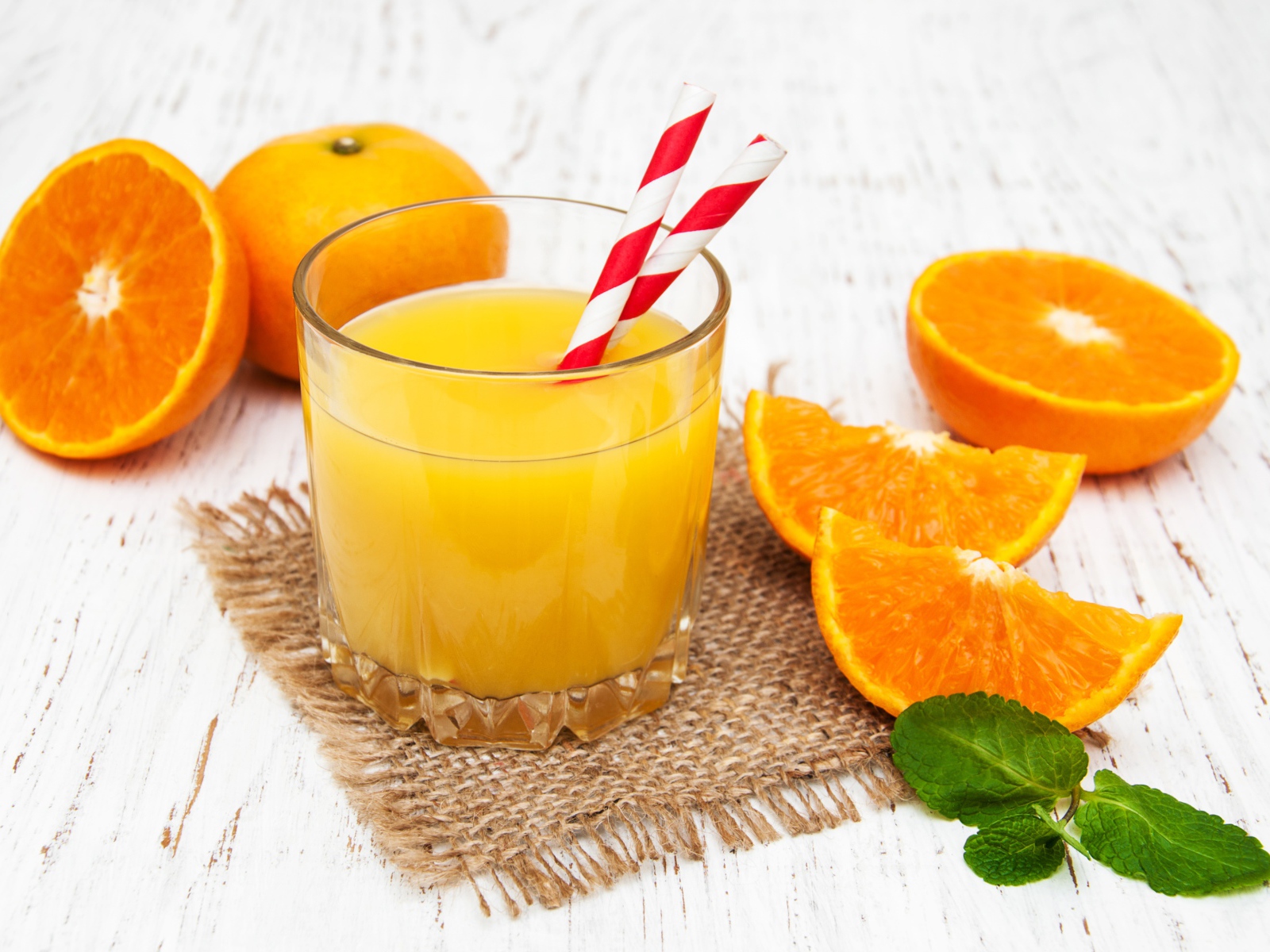 Стакан свежего сока на столе с апельсинами
