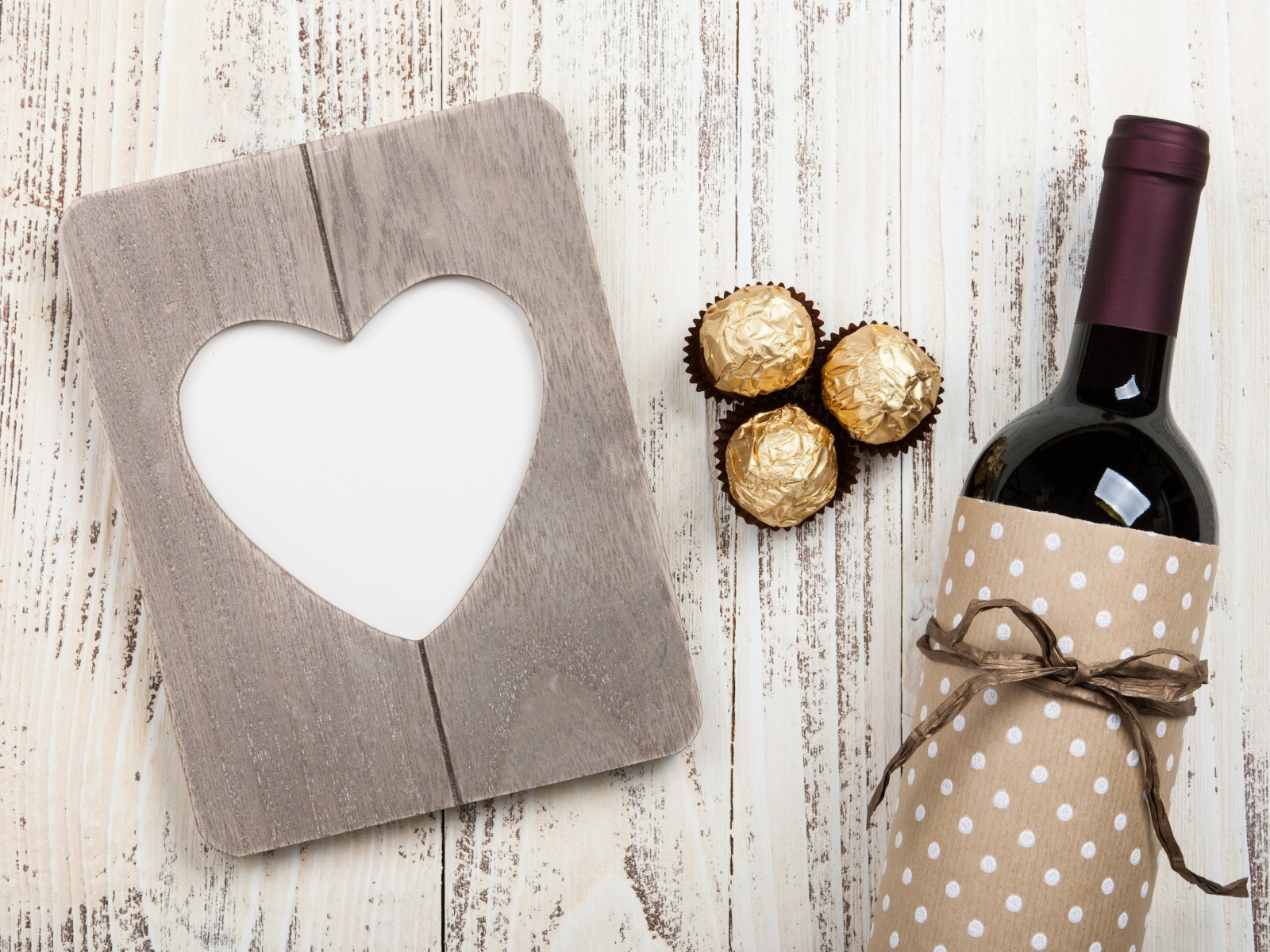 Бутылка вина на столе с конфетами и сердцем 