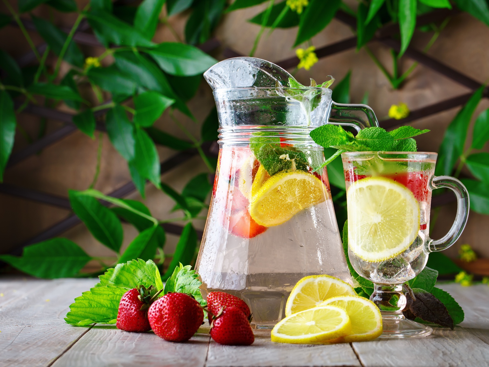 Холодный мохито в графине на столе с клубникой и лимоном