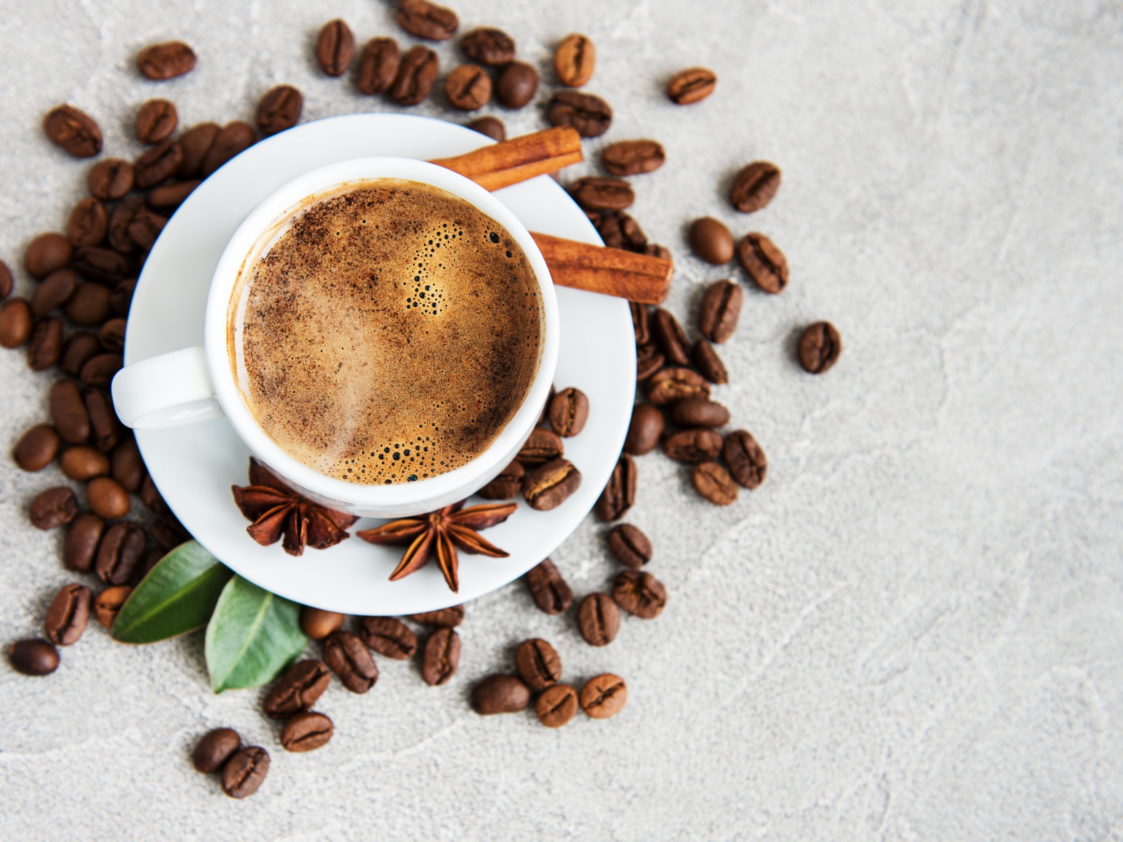 Чашка кофе с кофейными зернами на столе с корицей и бадьяном
